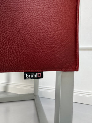 Gebrauchter roter Brühl Belami Designer Leder Sessel vor einer Wand, stilvoll und modern eingerichtet.