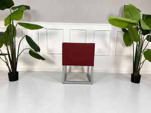 Gebrauchter roter Brühl Belami Designer Leder Sessel vor einer Wand, stilvoll und modern eingerichtet.