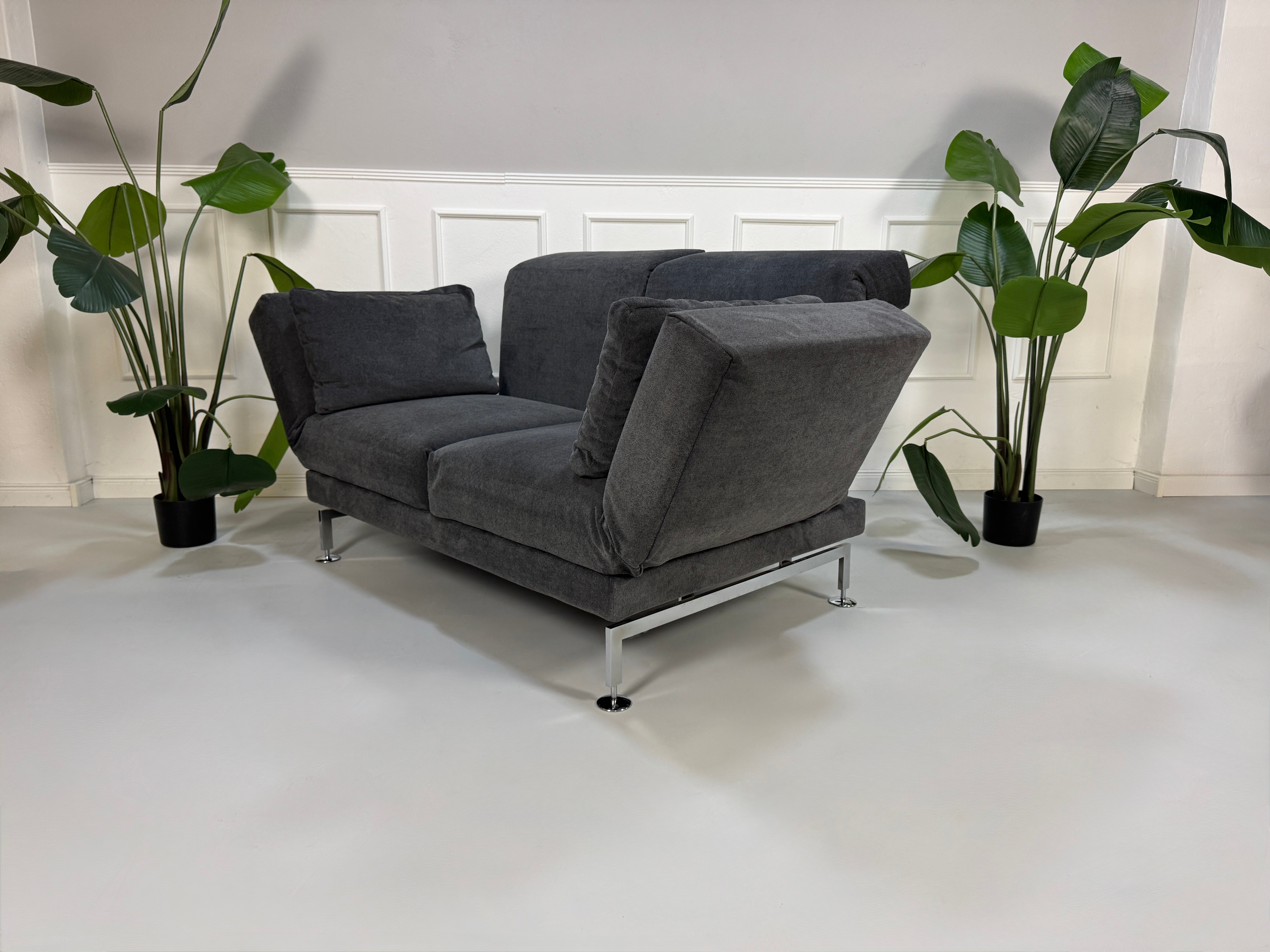 Gebrauchtes graues Stoffsofa Brühl Modell Moule Small vor einer modernen Wand