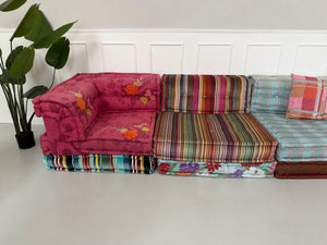 Gebrauchtes buntes Roche Bobois Mah Jong Designer Stoff Sofa vor einer Wand, stilvoll und modern eingerichtet.