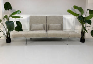 Gebrauchtes graues Brühl Roro Soft Designer Stoff Sofa vor einer Wand, stilvoll und modern eingerichtet.