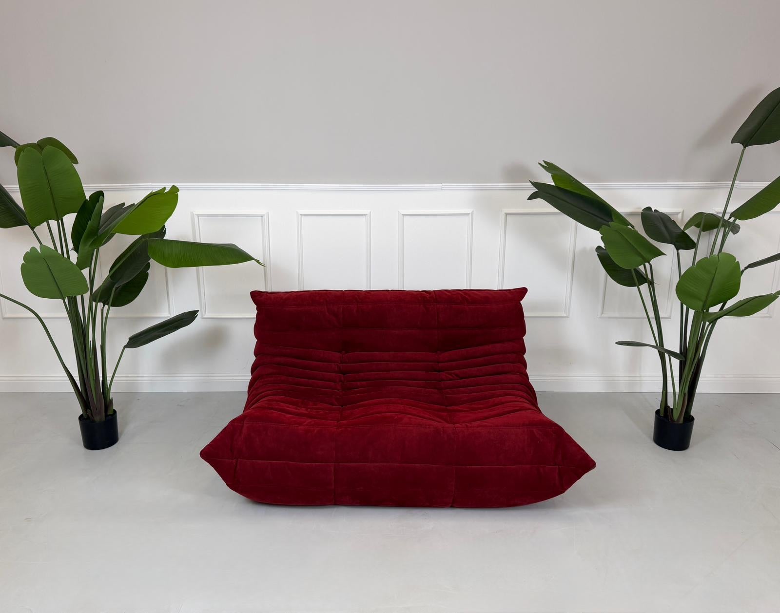 Gebrauchtes rotes Stoffsofa Ligne Roset Modell Togo vor einer modernen Wand.