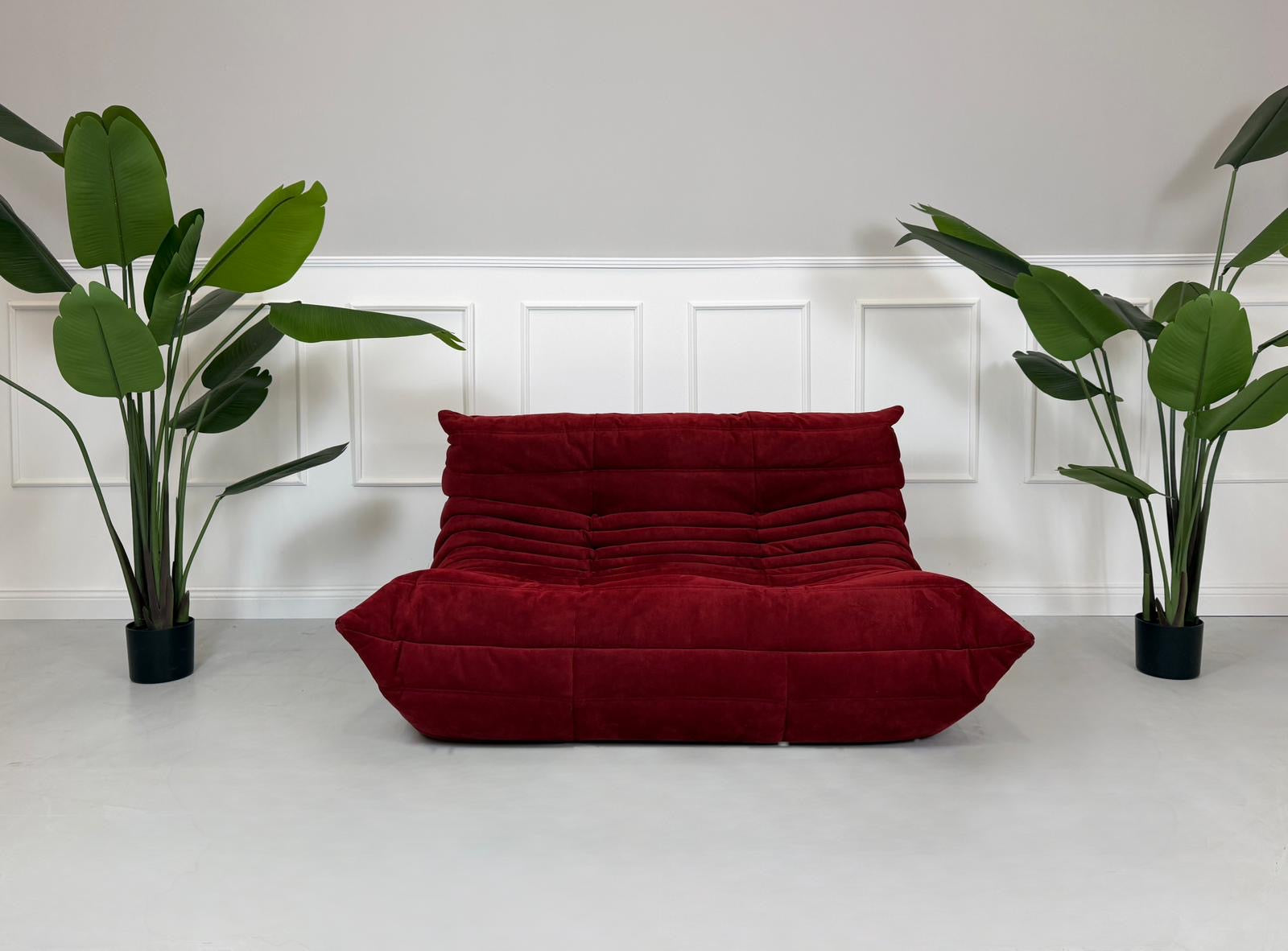 Gebrauchtes rotes Stoffsofa Ligne Roset Modell Togo vor einer modernen Wand.