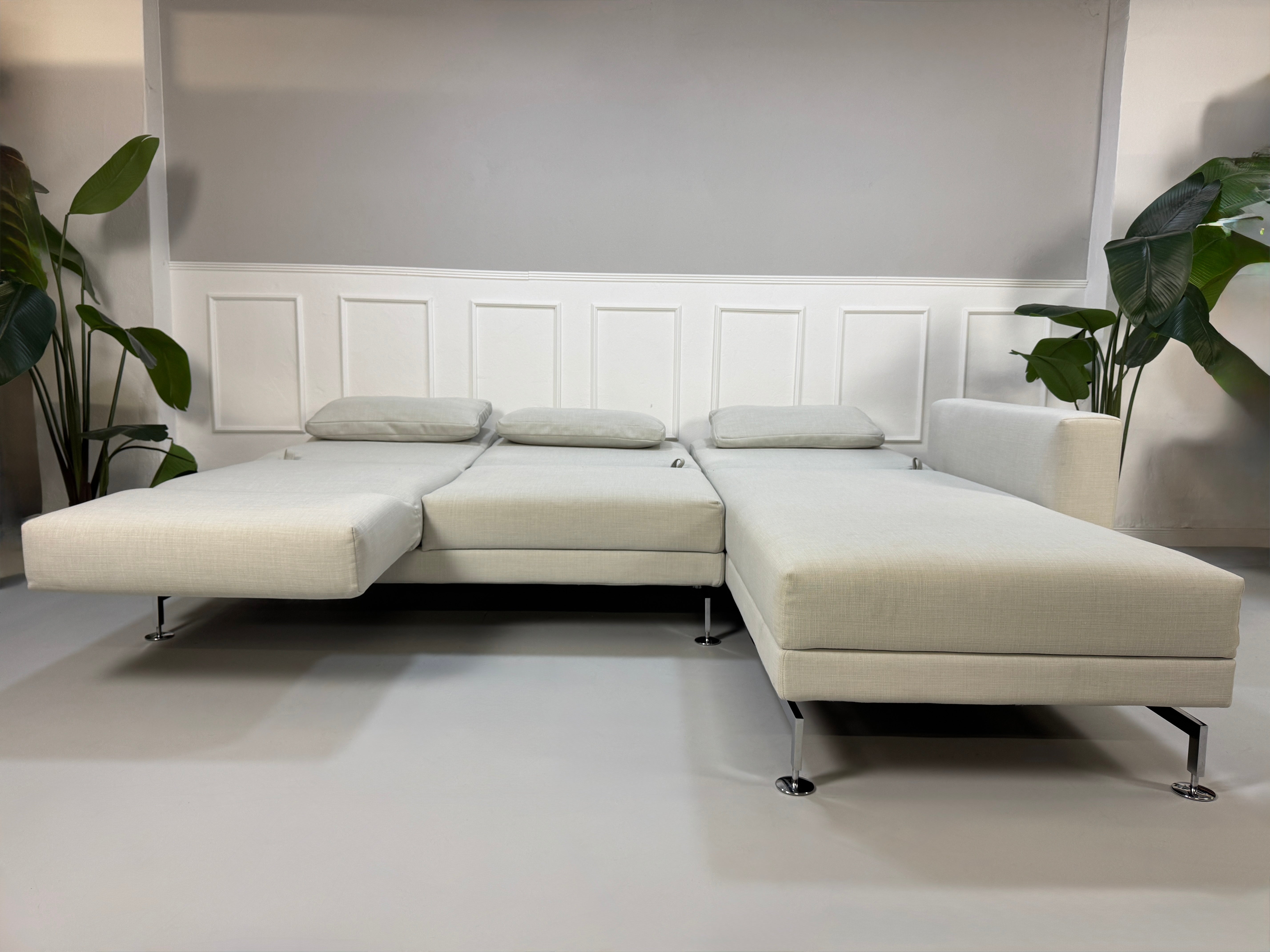 Gebrauchtes weißes Stoffsofa Brühl Modell Moule vor einer modernen Wand.