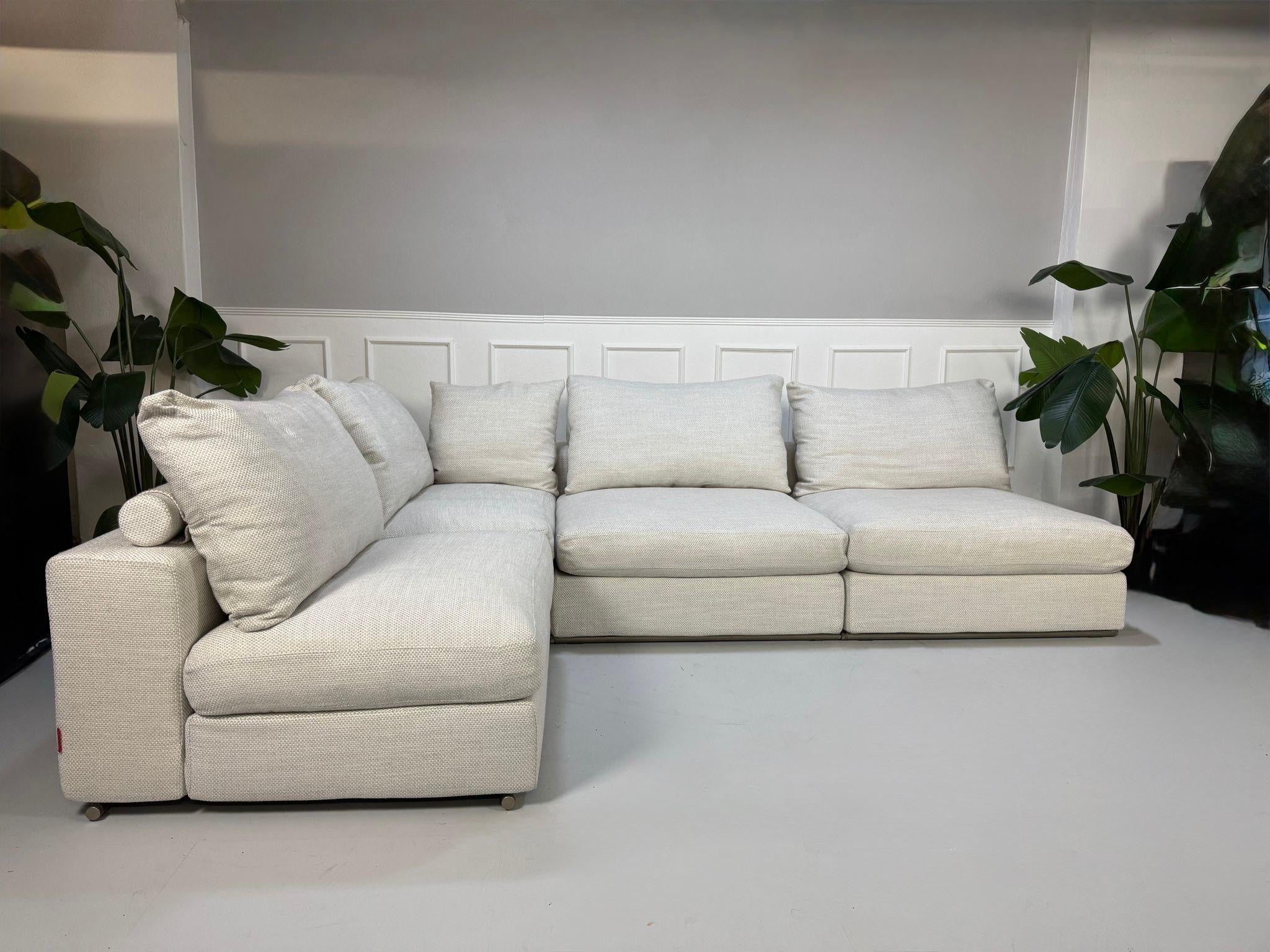 Gebrauchtes weißes Stoffsofa Flexform Modell Groundpiece vor einer modernen Wand.