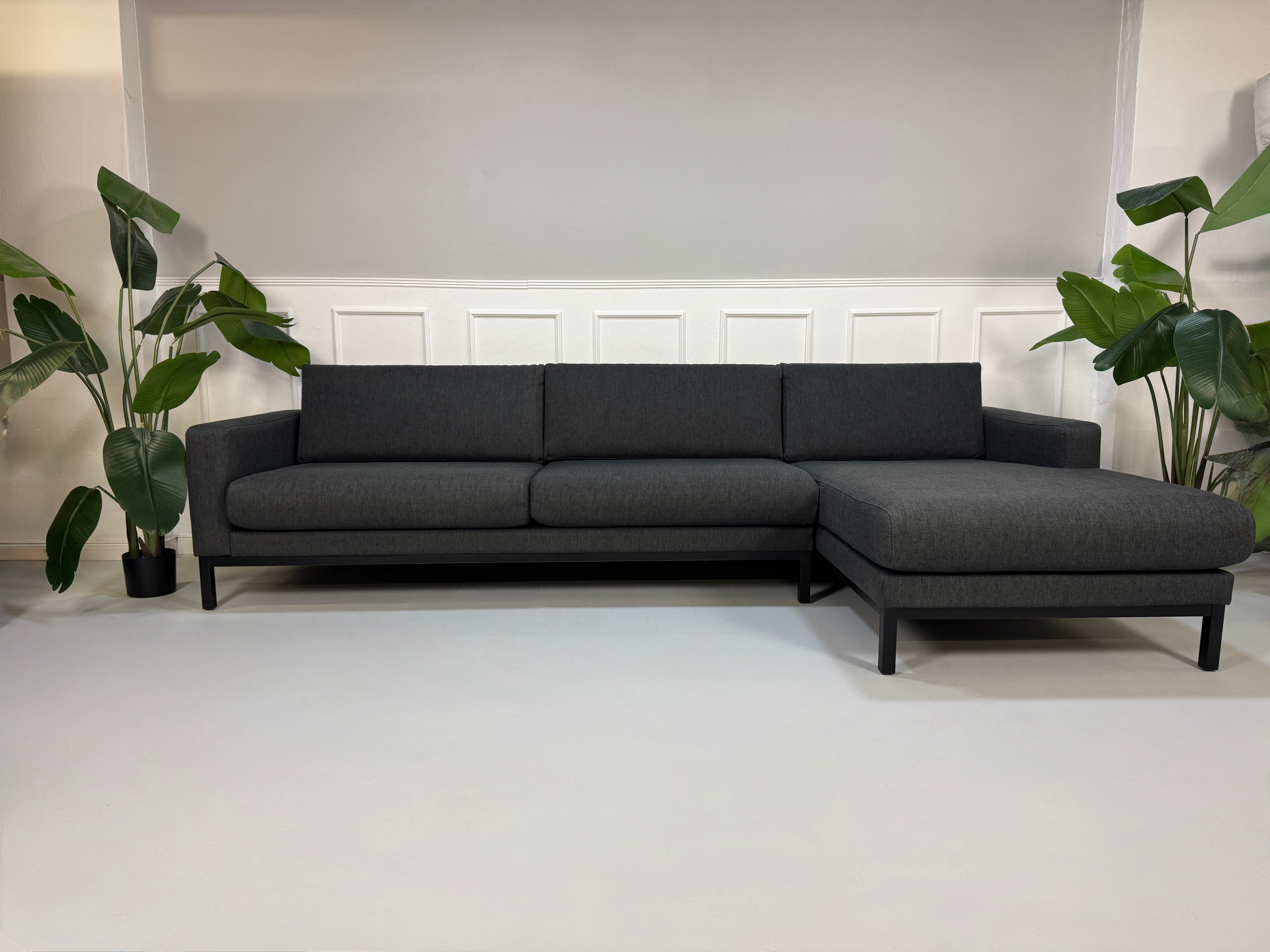Gebrauchtes graues Stoffsofa Bolia Modell North vor einer modernen Wand.
