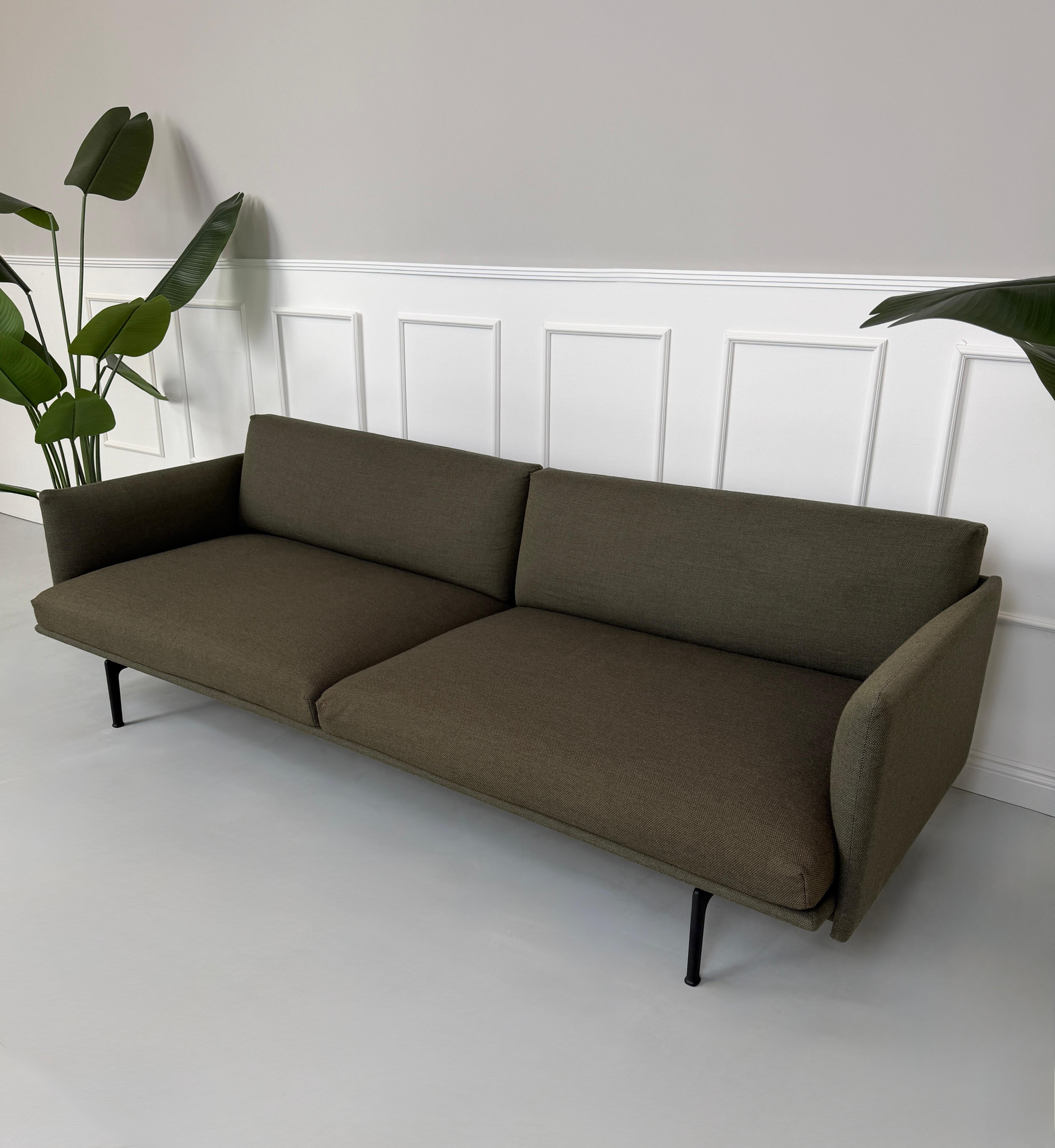 Gebrauchtes grünes Muuto Outline Designer Stoff Sofa vor einer Wand, stilvoll und modern eingerichtet.