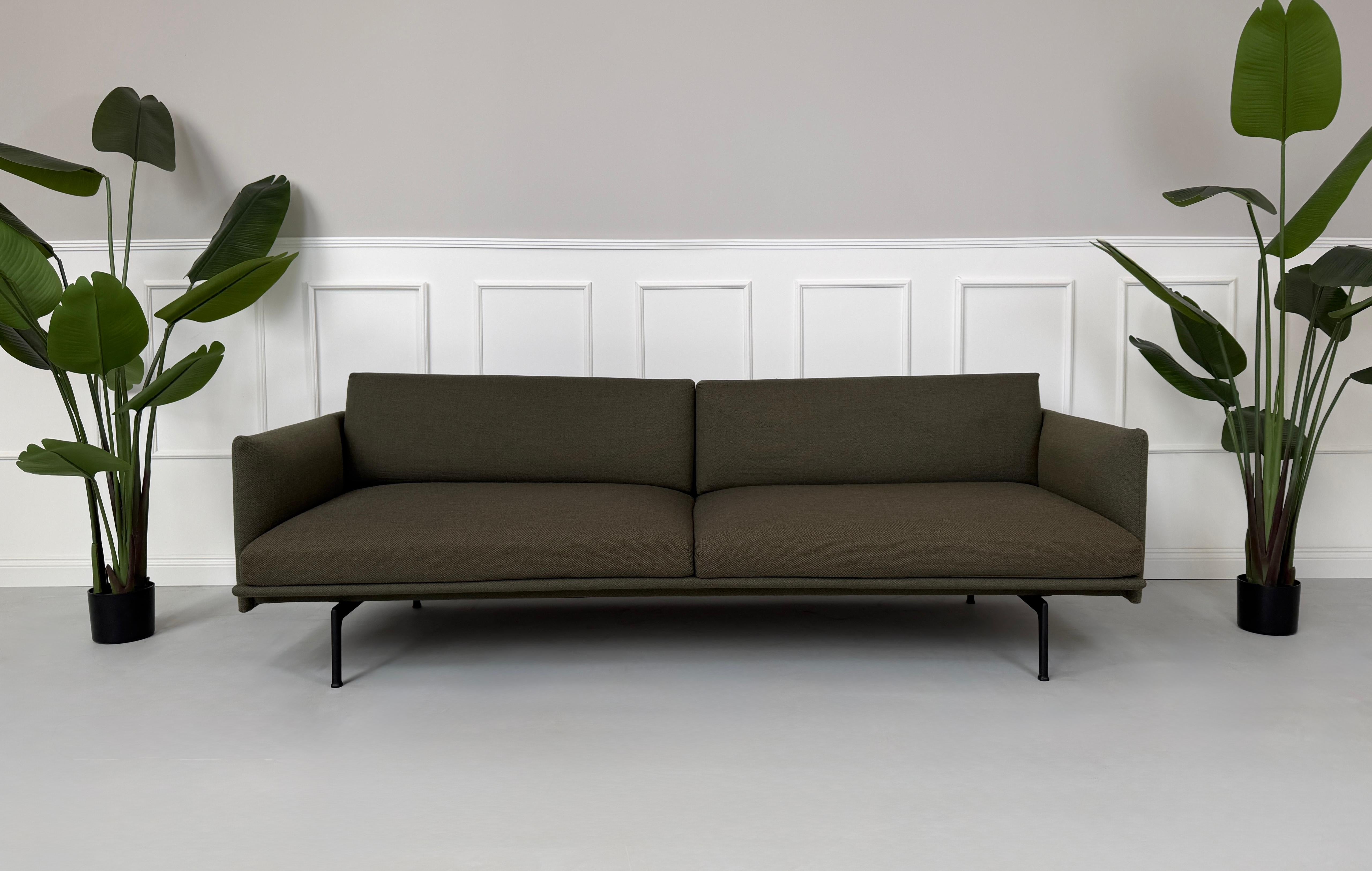 Gebrauchtes grünes Muuto Outline Designer Stoff Sofa vor einer Wand, stilvoll und modern eingerichtet.
