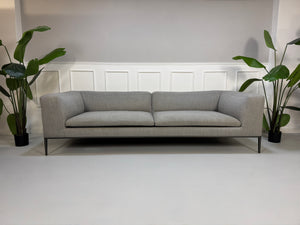 Gebrauchtes graues B&B Italia Michel  Designer Stoff Sofa vor einer Wand, stilvoll und modern eingerichtet.