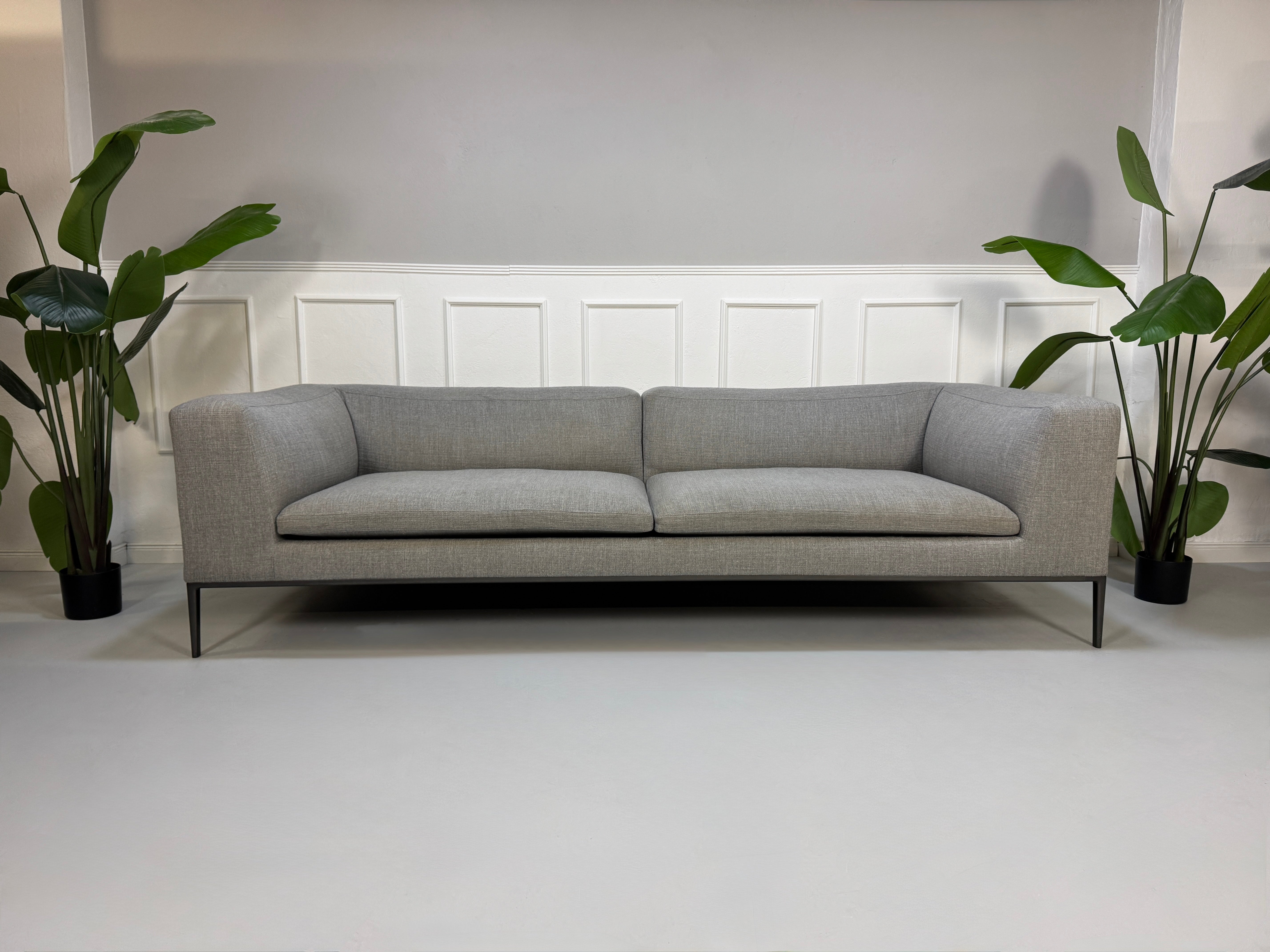 Gebrauchtes graues B&B Italia Michel  Designer Stoff Sofa vor einer Wand, stilvoll und modern eingerichtet.
