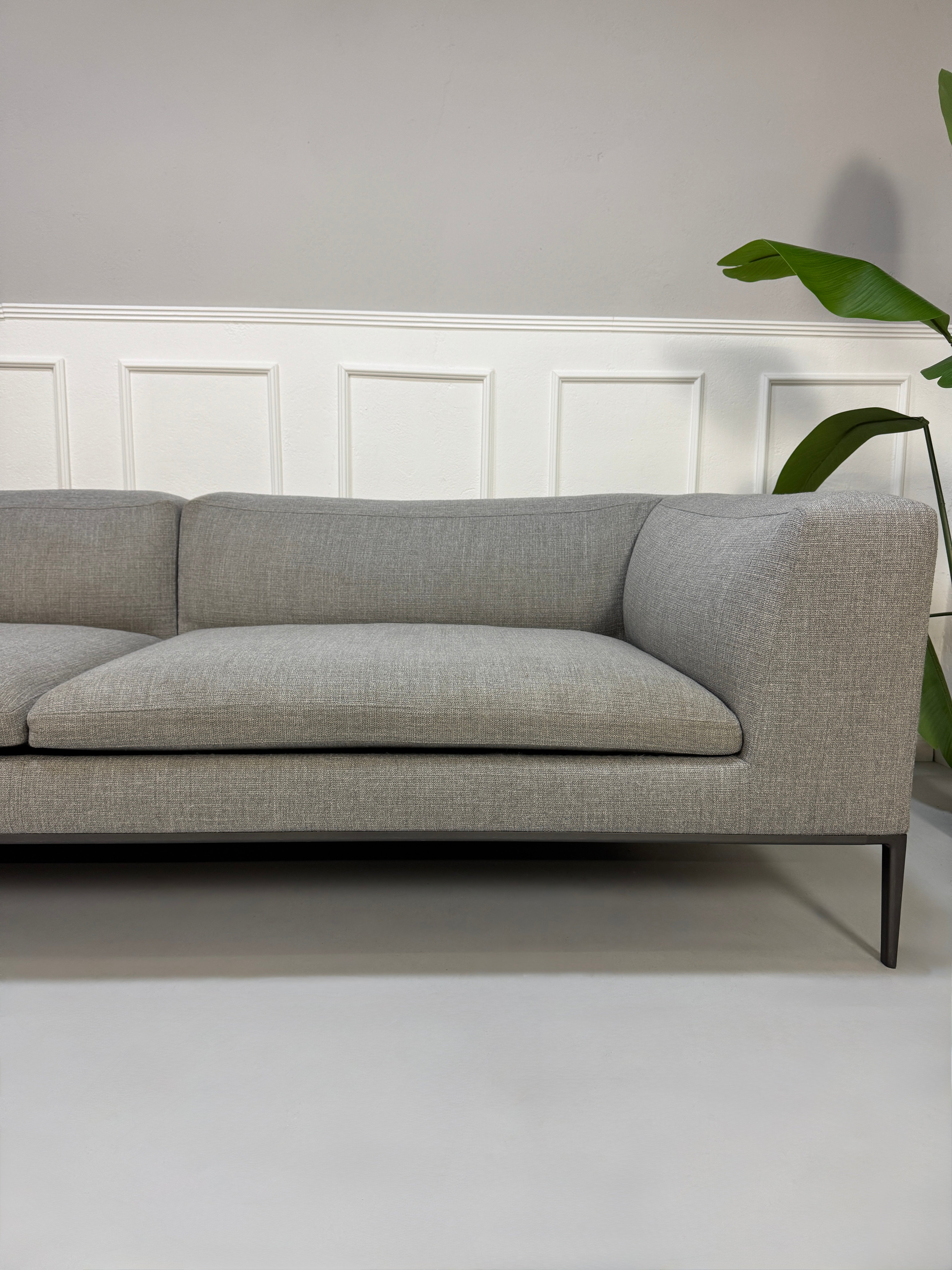 Gebrauchtes graues B&B Italia Michel  Designer Stoff Sofa vor einer Wand, stilvoll und modern eingerichtet.