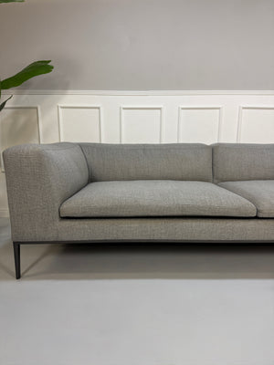 Gebrauchtes graues B&B Italia Michel  Designer Stoff Sofa vor einer Wand, stilvoll und modern eingerichtet.