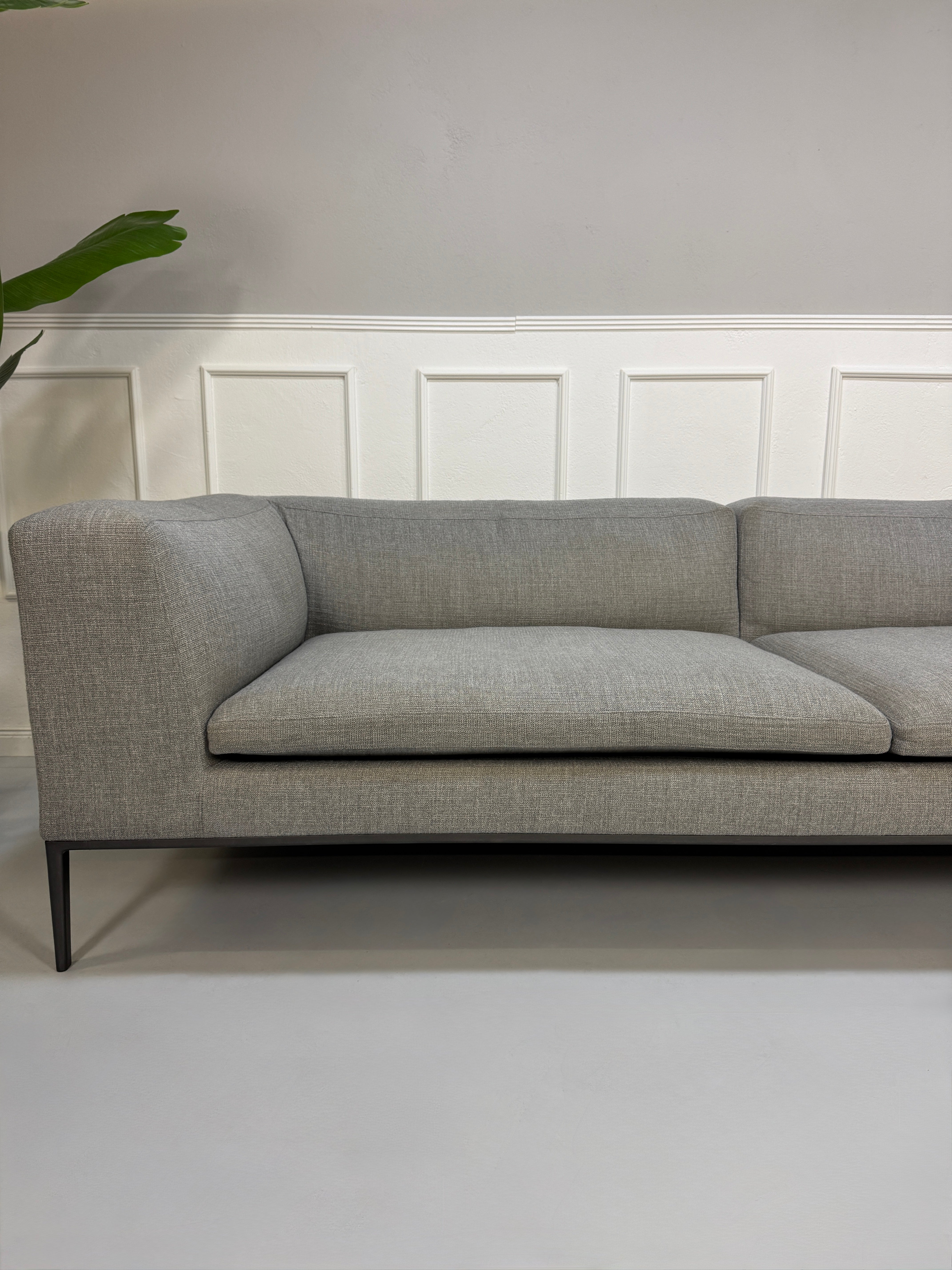 Gebrauchtes graues B&B Italia Michel  Designer Stoff Sofa vor einer Wand, stilvoll und modern eingerichtet.