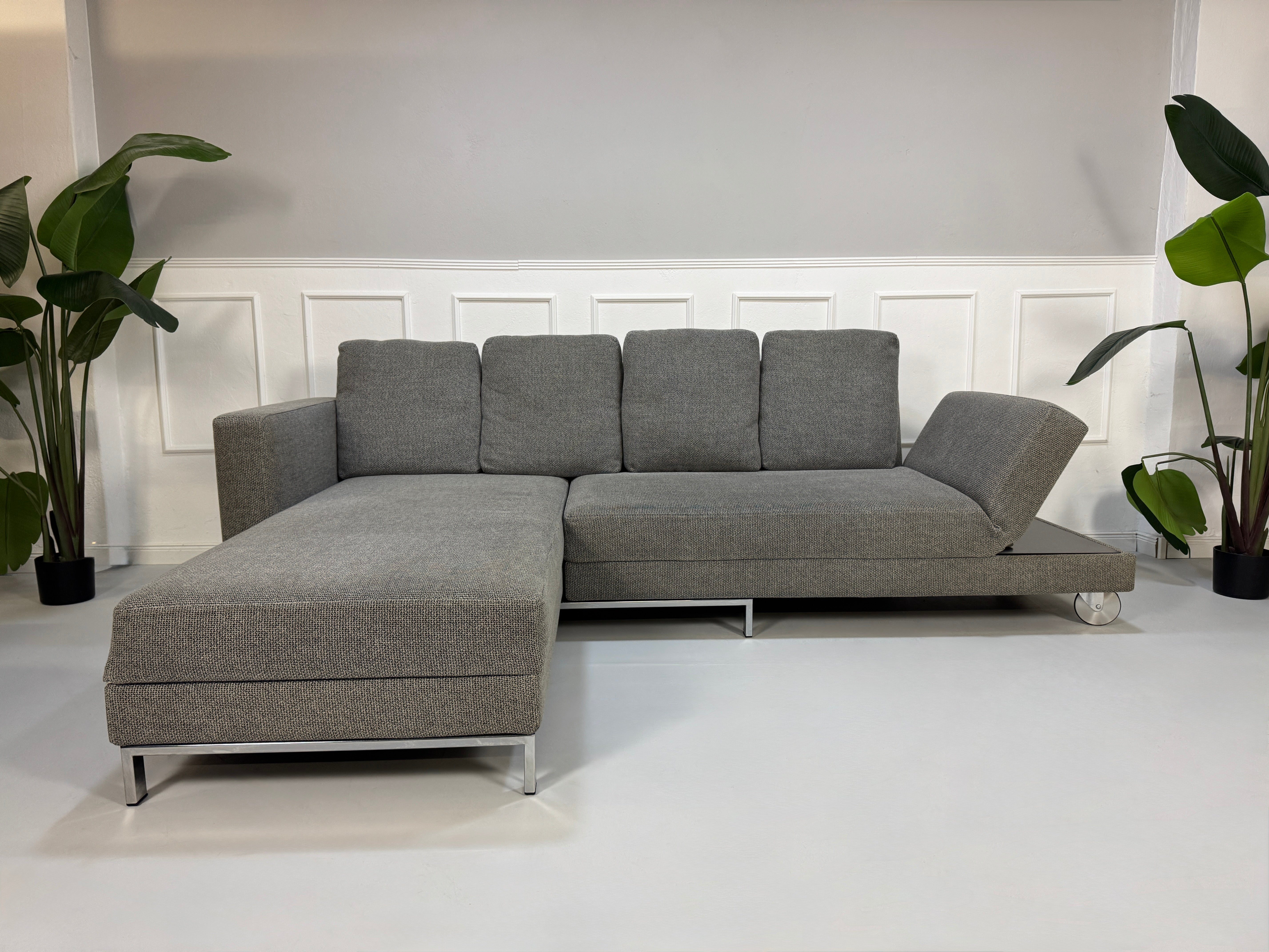 Gebrauchtes graues Brühl Fourtwo Designer Stoff Sofa vor einer Wand, stilvoll und modern eingerichtet.