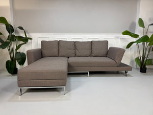 Gebrauchtes braunes Brühl Fourtwo Designer Stoff Sofa vor einer Wand, stilvoll und modern eingerichtet.
