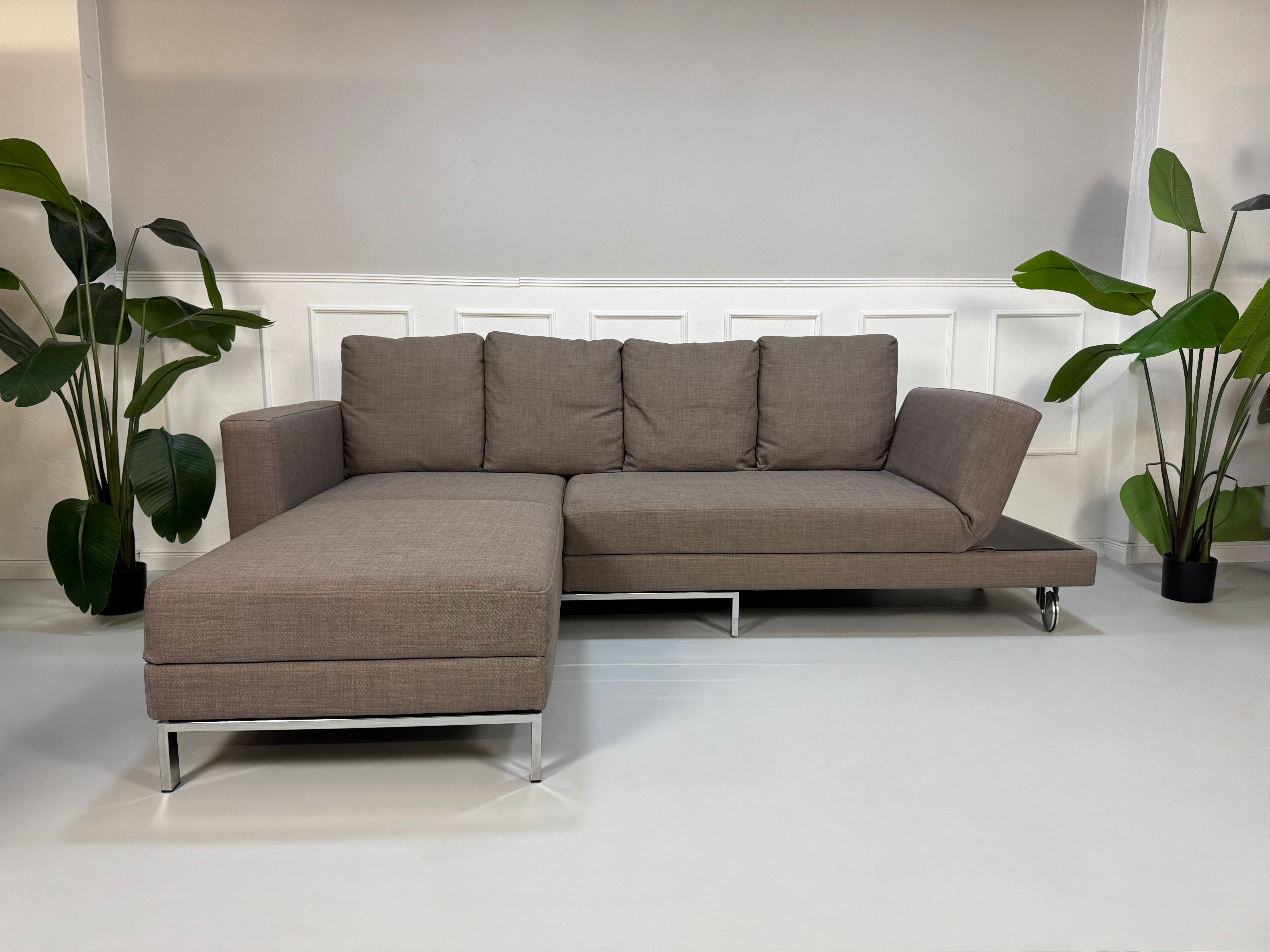 Gebrauchtes braunes Brühl Fourtwo Designer Stoff Sofa vor einer Wand, stilvoll und modern eingerichtet.
