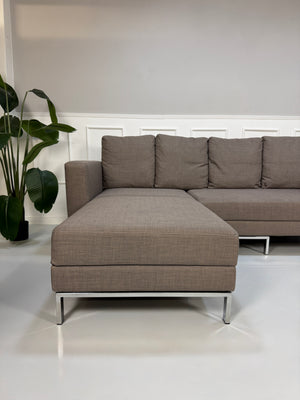 Gebrauchtes braunes Brühl Fourtwo Designer Stoff Sofa vor einer Wand, stilvoll und modern eingerichtet.