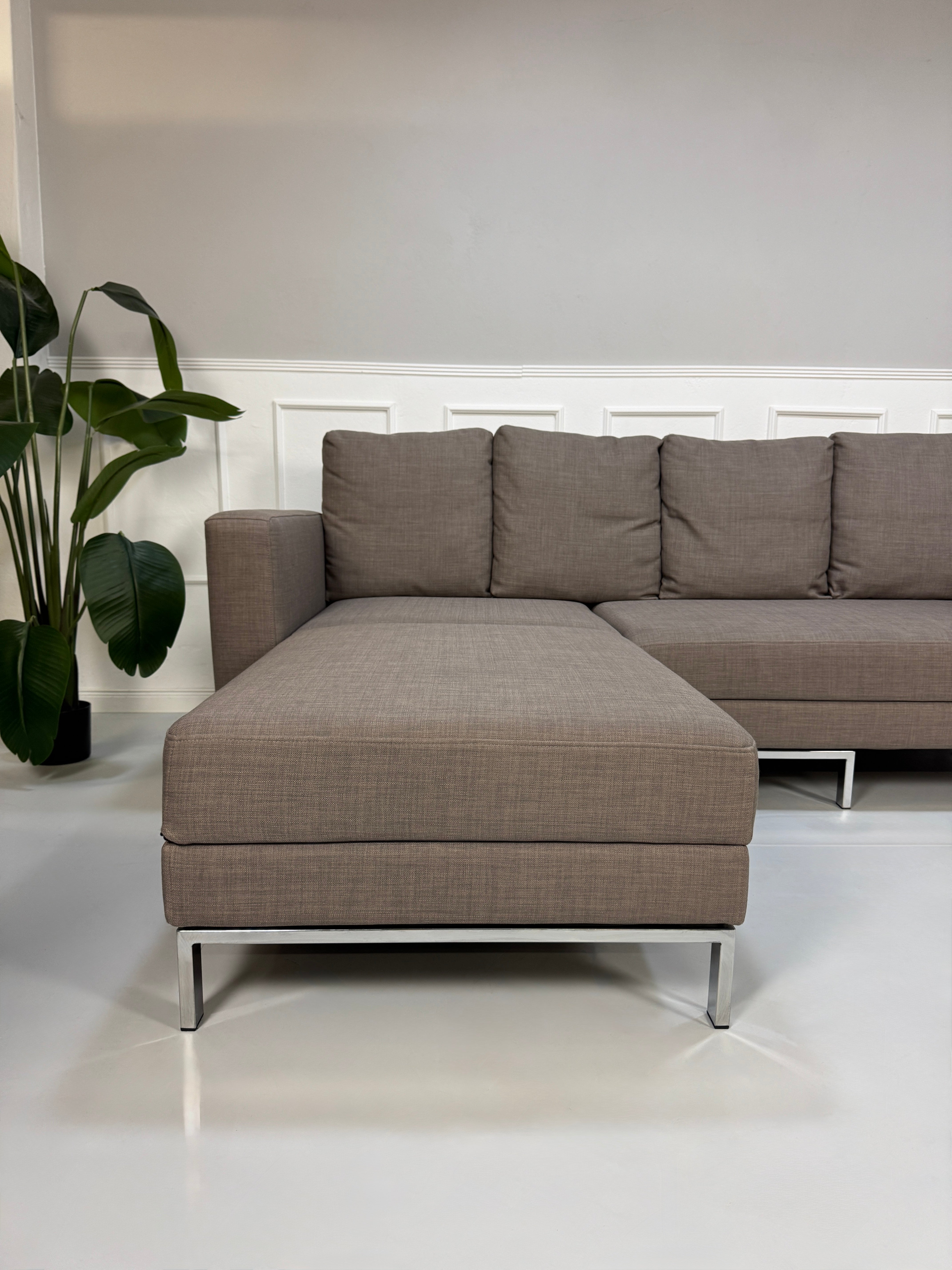 Gebrauchtes braunes Brühl Fourtwo Designer Stoff Sofa vor einer Wand, stilvoll und modern eingerichtet.