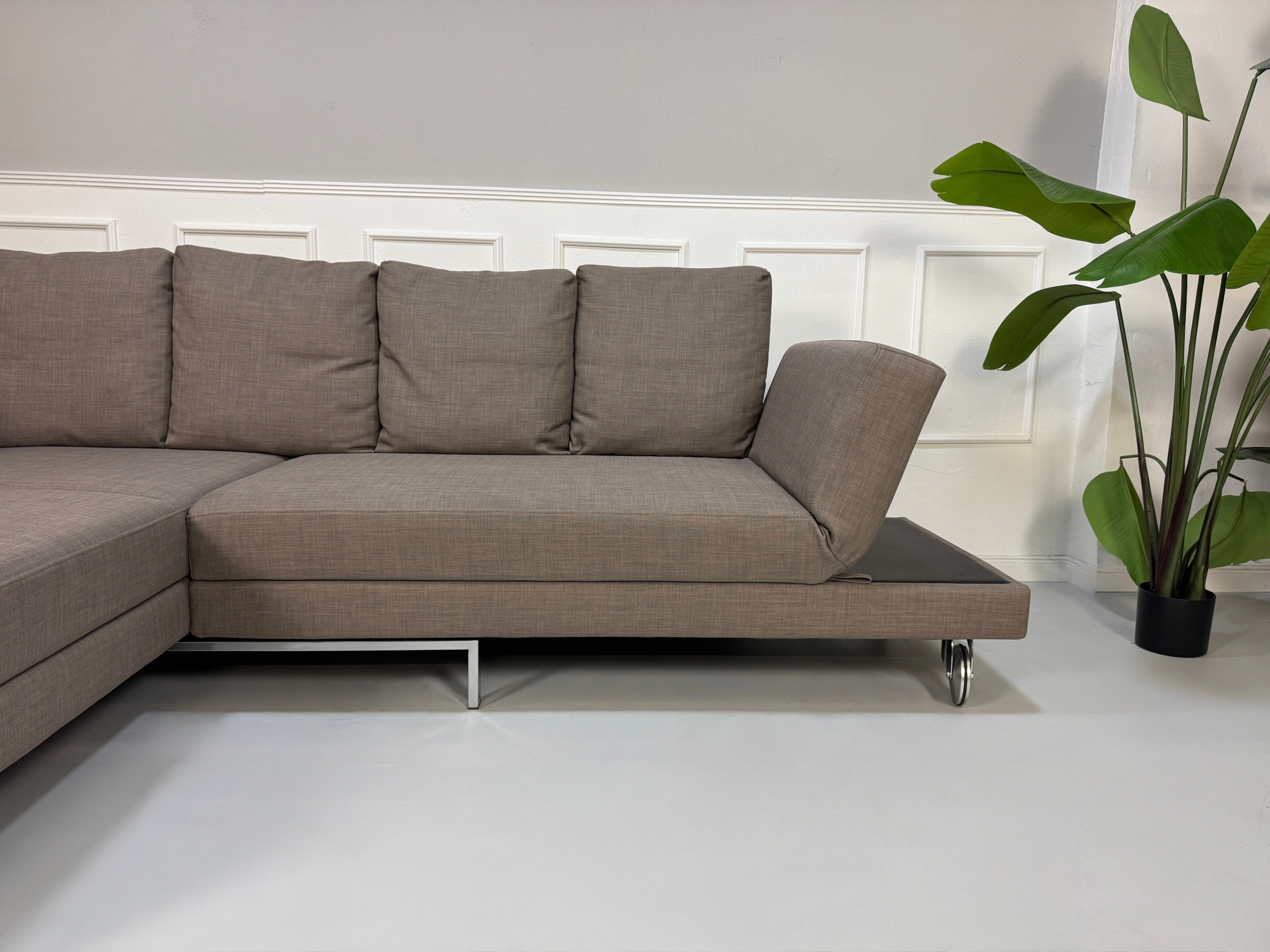 Gebrauchtes braunes Brühl Fourtwo Designer Stoff Sofa vor einer Wand, stilvoll und modern eingerichtet.
