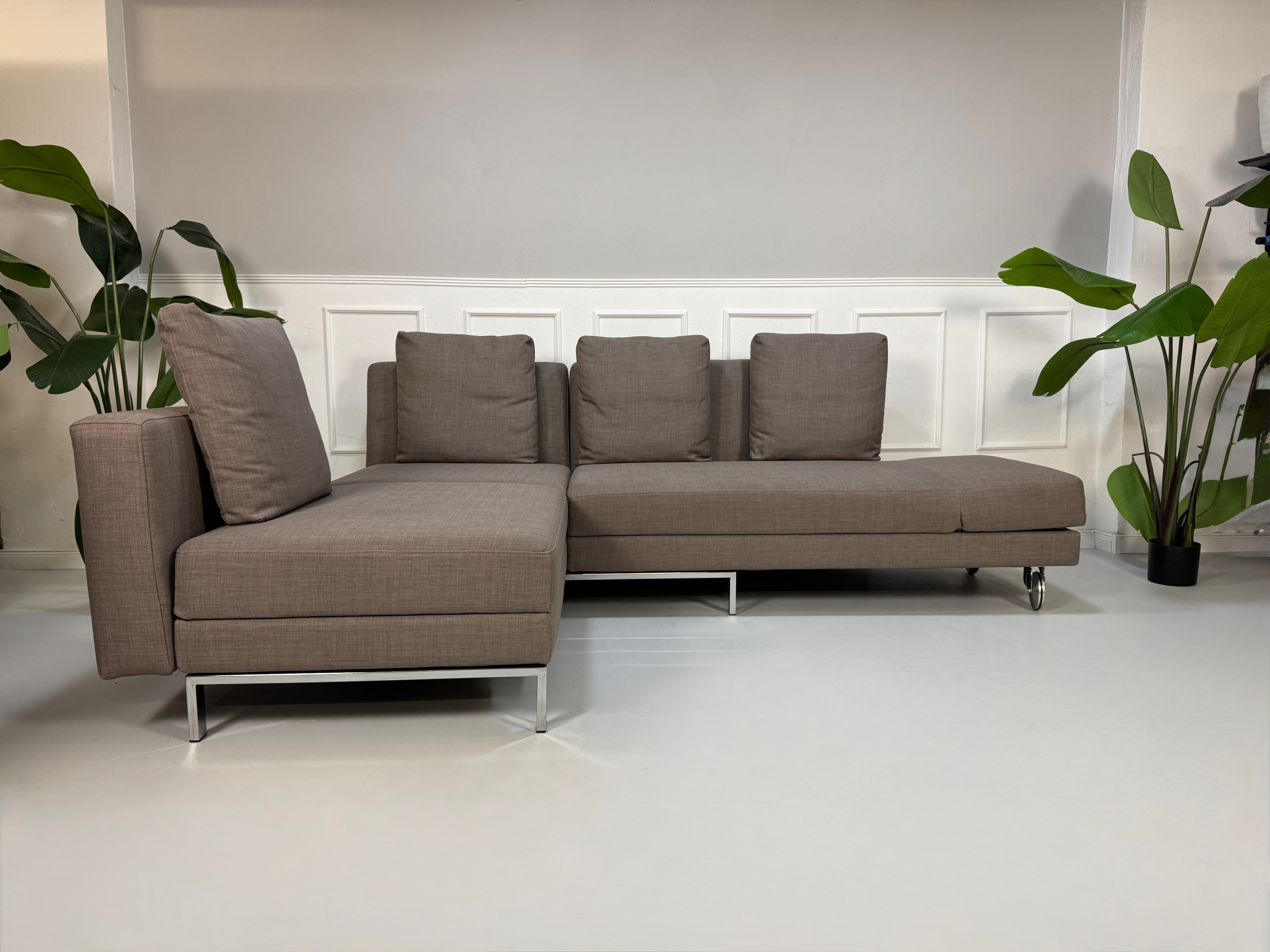 Gebrauchtes braunes Brühl Fourtwo Designer Stoff Sofa vor einer Wand, stilvoll und modern eingerichtet.