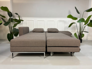 Gebrauchtes braunes Brühl Fourtwo Designer Stoff Sofa vor einer Wand, stilvoll und modern eingerichtet.