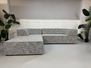 Gebrauchtes graues COR Trio Designer Stoff Sofa vor einer Wand, stilvoll und modern eingerichtet.