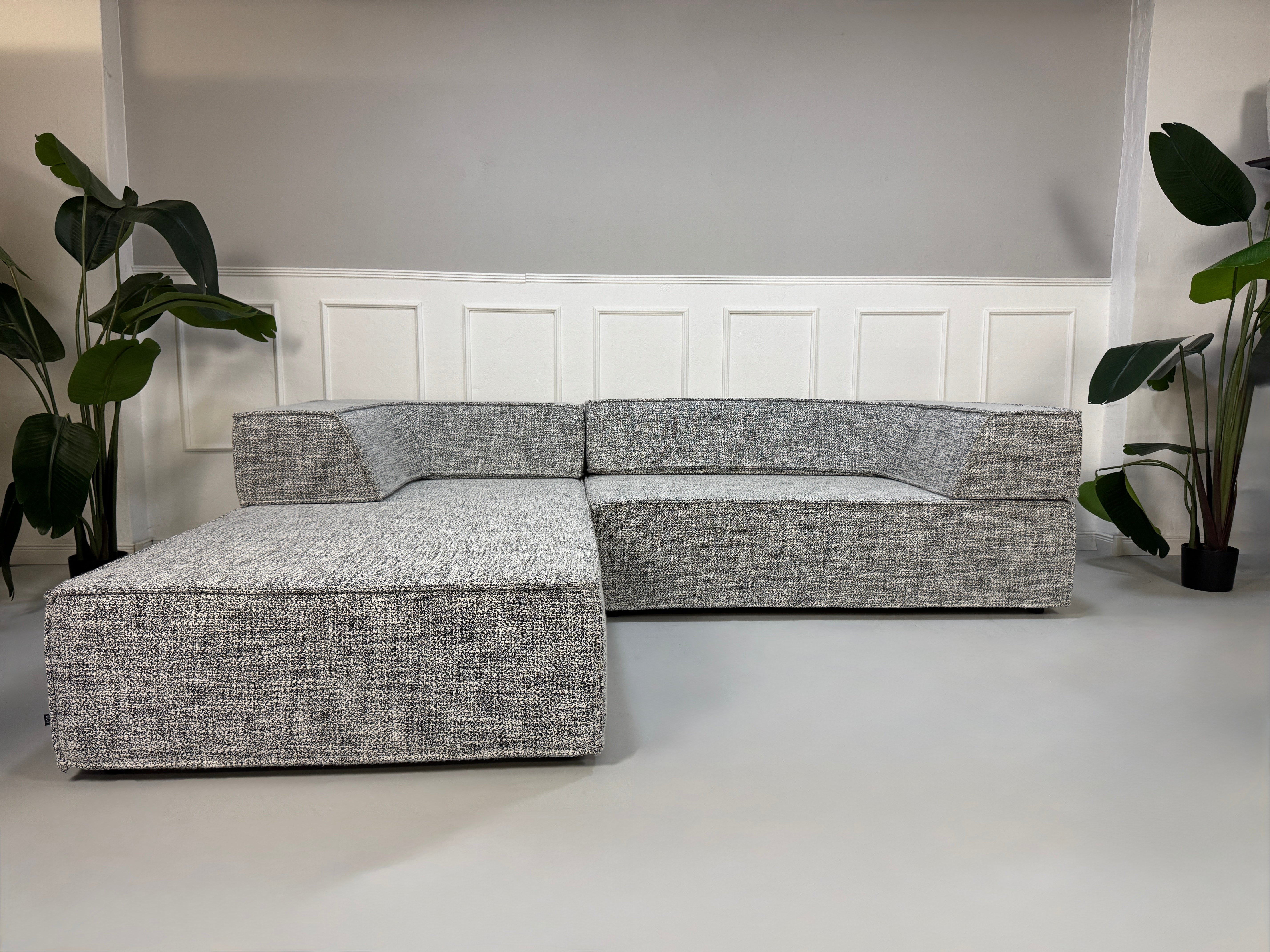 Gebrauchtes graues COR Trio Designer Stoff Sofa vor einer Wand, stilvoll und modern eingerichtet.