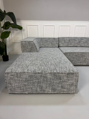 Gebrauchtes graues COR Trio Designer Stoff Sofa vor einer Wand, stilvoll und modern eingerichtet.