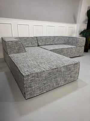Gebrauchtes graues COR Trio Designer Stoff Sofa vor einer Wand, stilvoll und modern eingerichtet.