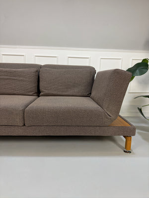 Gebrauchtes braunes Brühl Moule Designer Stoff Sofa vor einer Wand, stilvoll und modern eingerichtet.