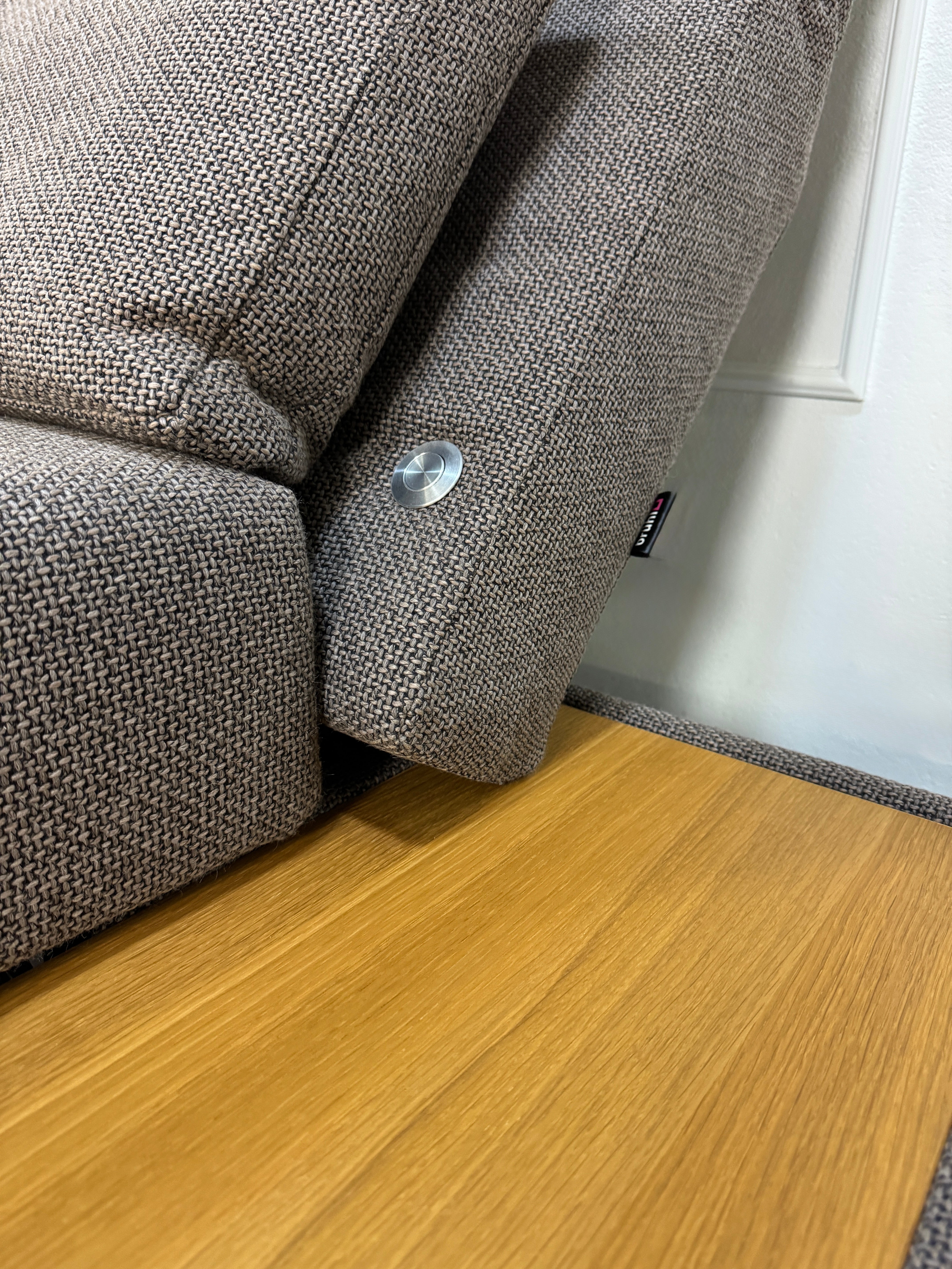 Gebrauchtes braunes Brühl Moule Designer Stoff Sofa vor einer Wand, stilvoll und modern eingerichtet.