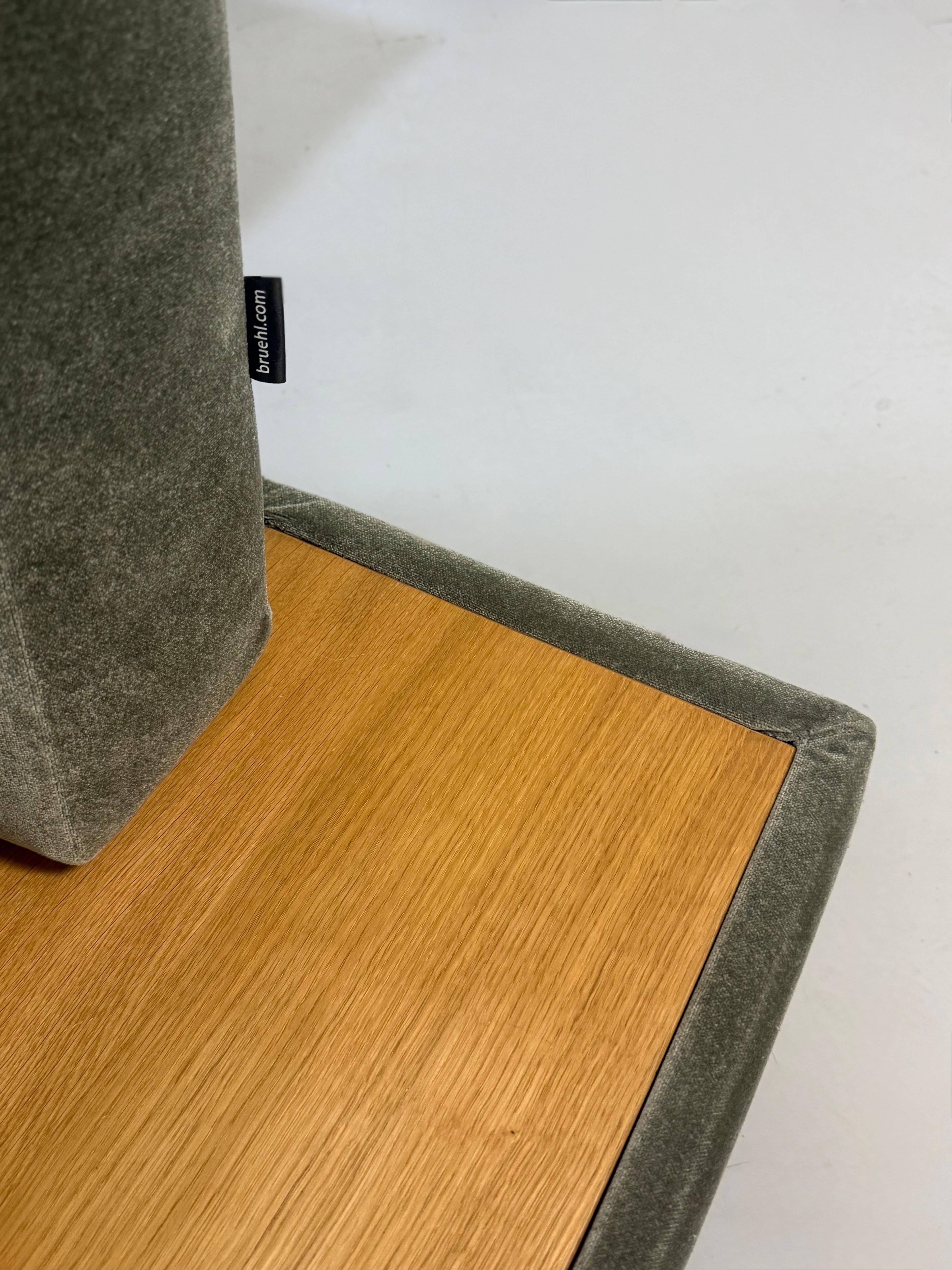 Gebrauchtes grün-graues Stoff Sofa Brühl Modell Moule Large vor einer modernen Wand.