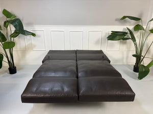 Gebrauchtes braunes Ledersofa Brühl Modell Roro Soft vor einer modernen Wand.