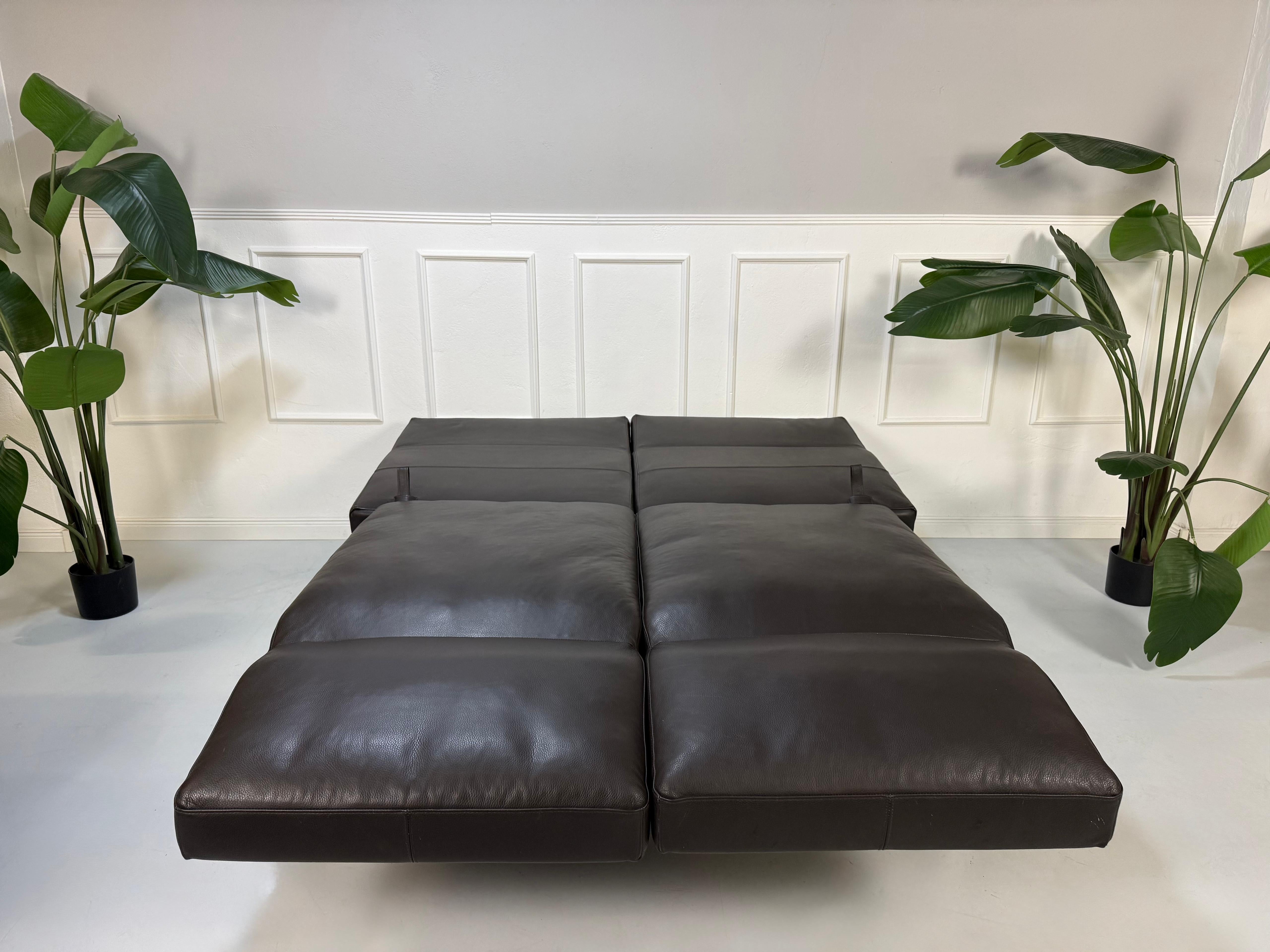 Gebrauchtes braunes Ledersofa Brühl Modell Roro Soft vor einer modernen Wand.