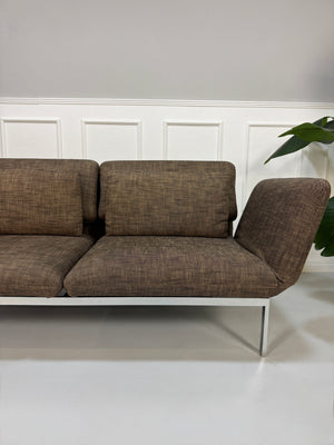 Gebrauchtes braunes Stoff Sofa Brühl Modell Roro vor einer modernen Wand.