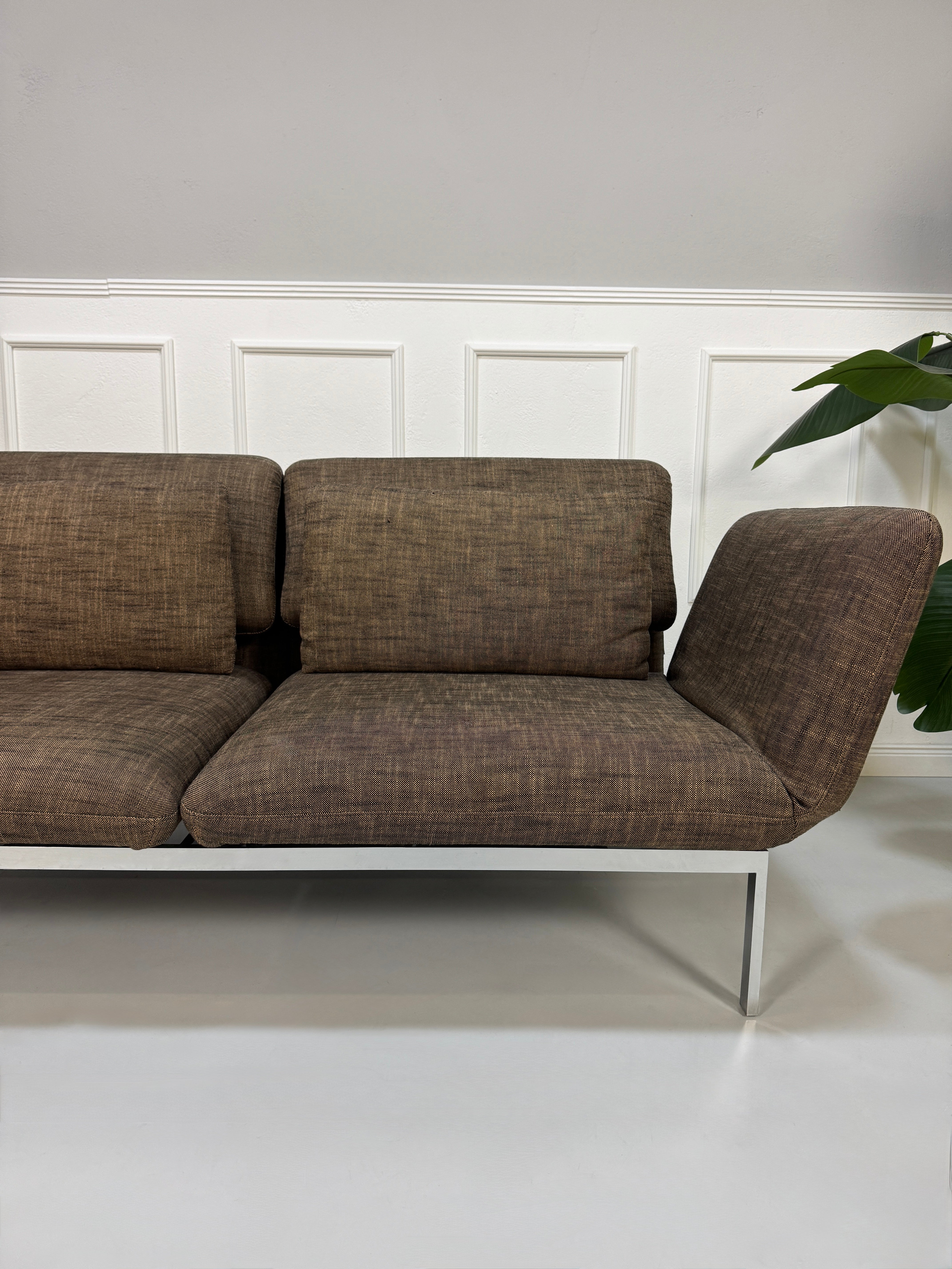 Gebrauchtes braunes Stoff Sofa Brühl Modell Roro vor einer modernen Wand.