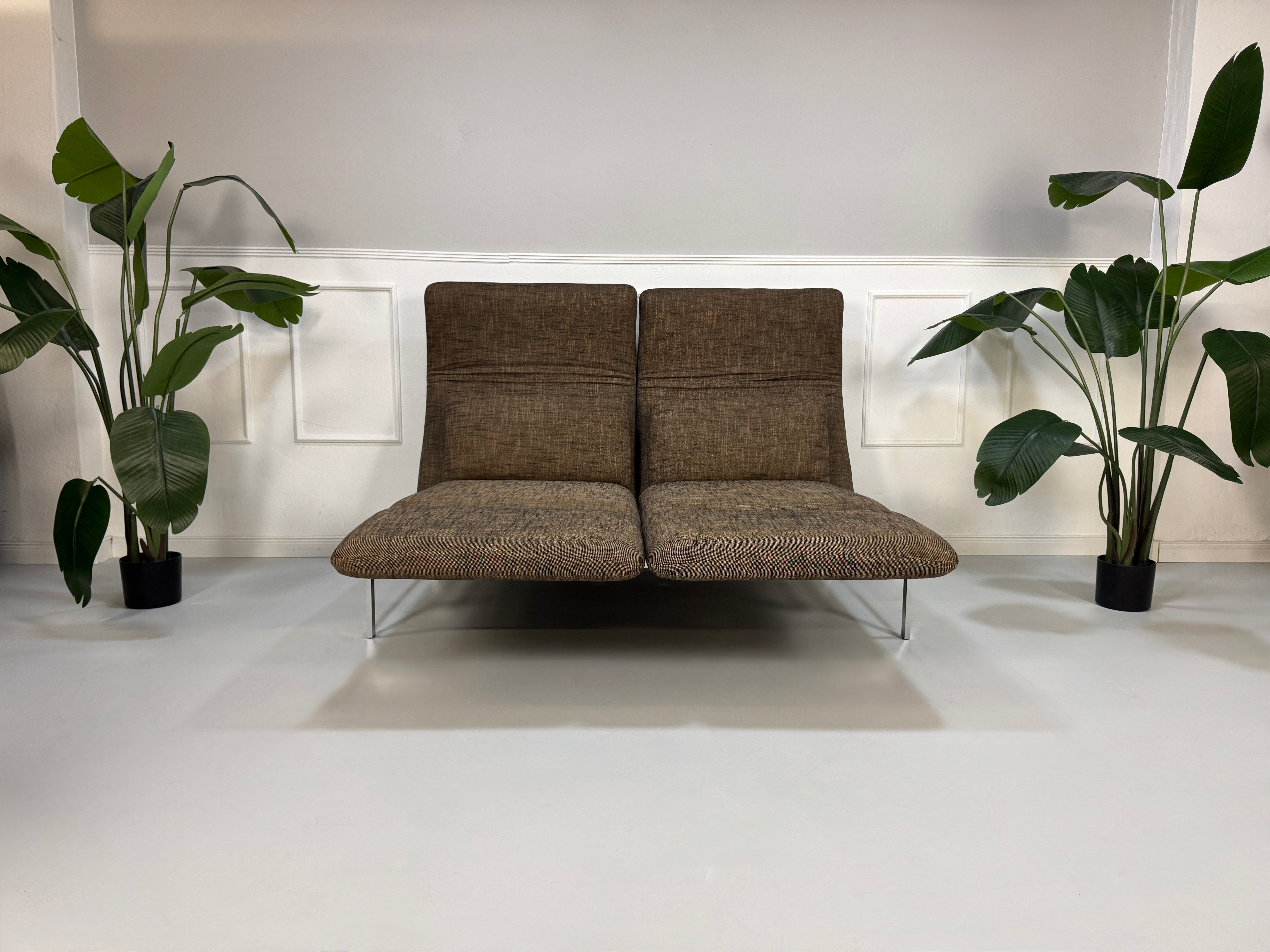 Gebrauchtes braunes Stoff Sofa Brühl Modell Roro vor einer modernen Wand.