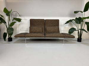 Gebrauchtes braunes Stoff Sofa Brühl Modell Roro vor einer modernen Wand.