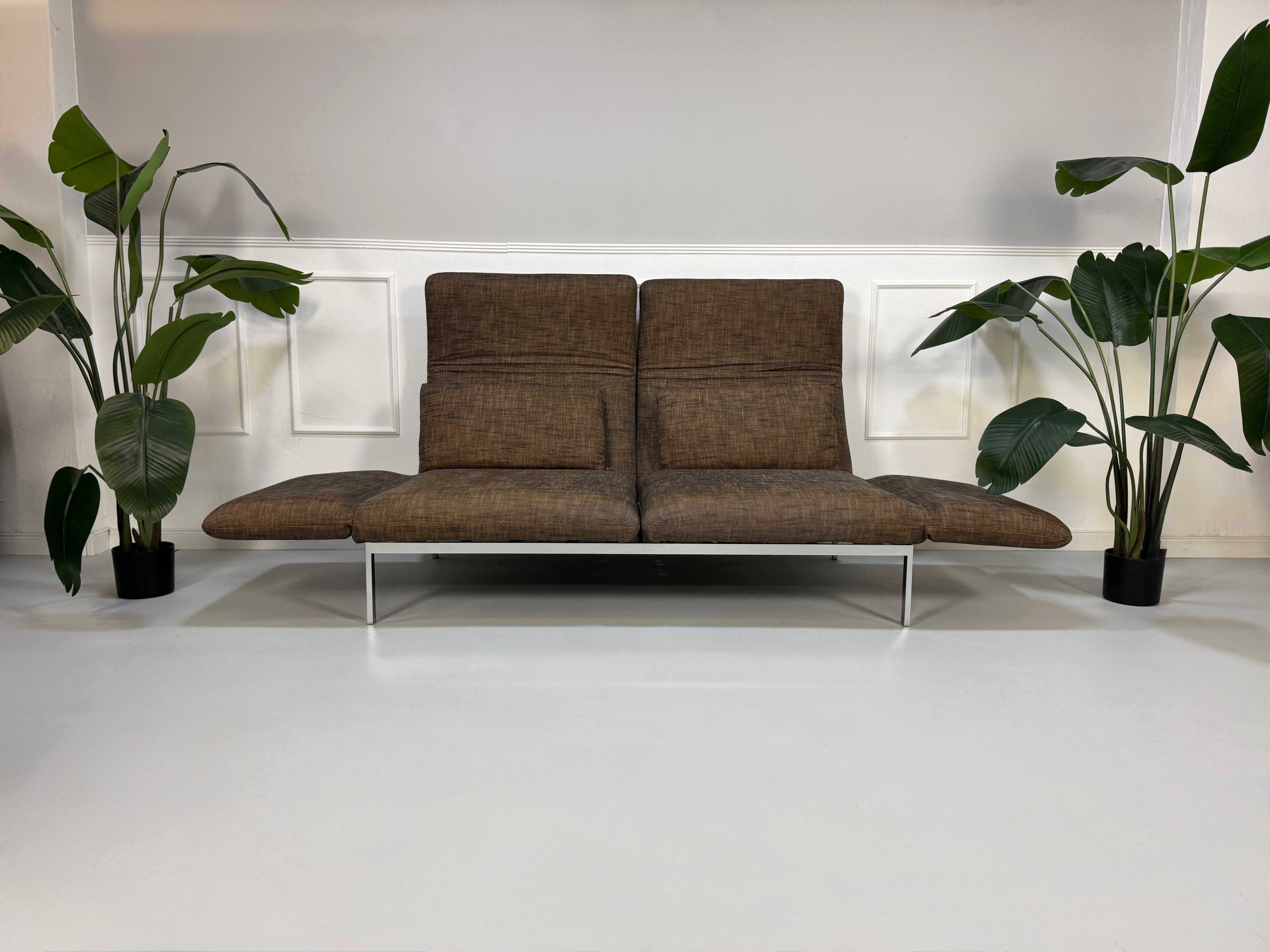 Gebrauchtes braunes Stoff Sofa Brühl Modell Roro vor einer modernen Wand.