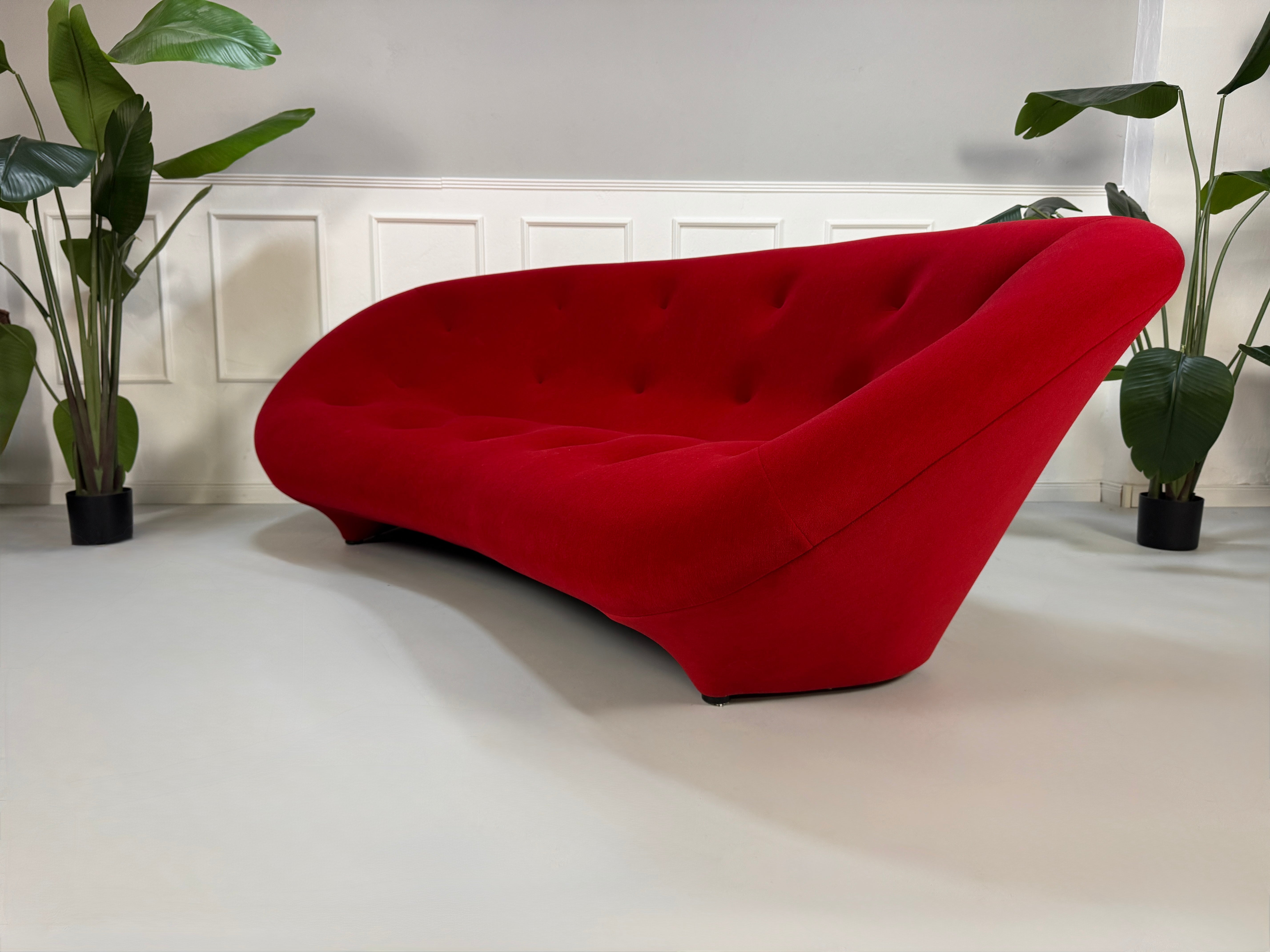 Gebrauchtes rotes Stoff Sofa Ligne Roset Modell Ploum vor einer modernen Wand.