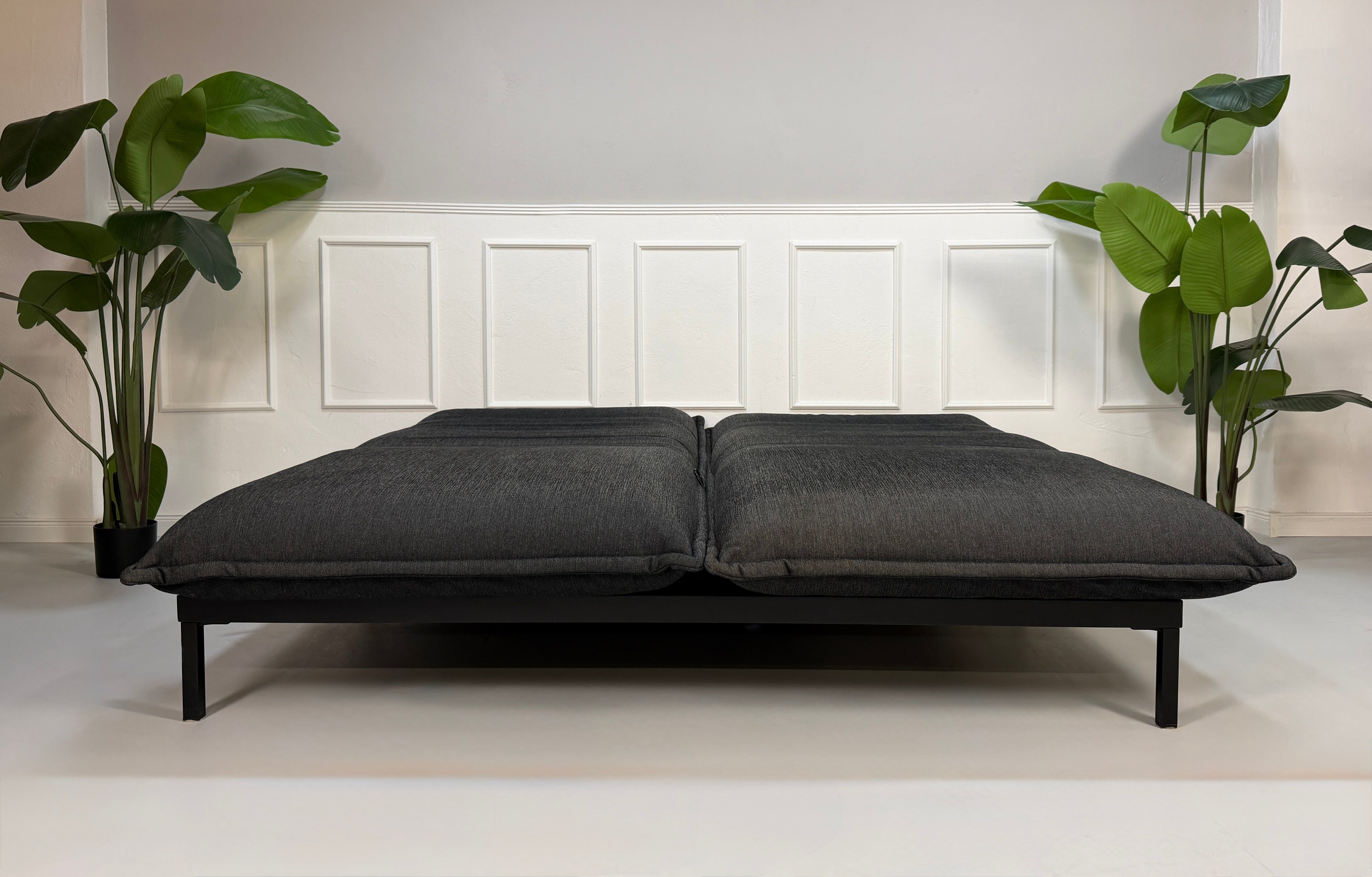 Gebrauchtes graues Rolf Benz Nova Designer Stoff Sofa vor einer Wand, stilvoll und modern eingerichtet.