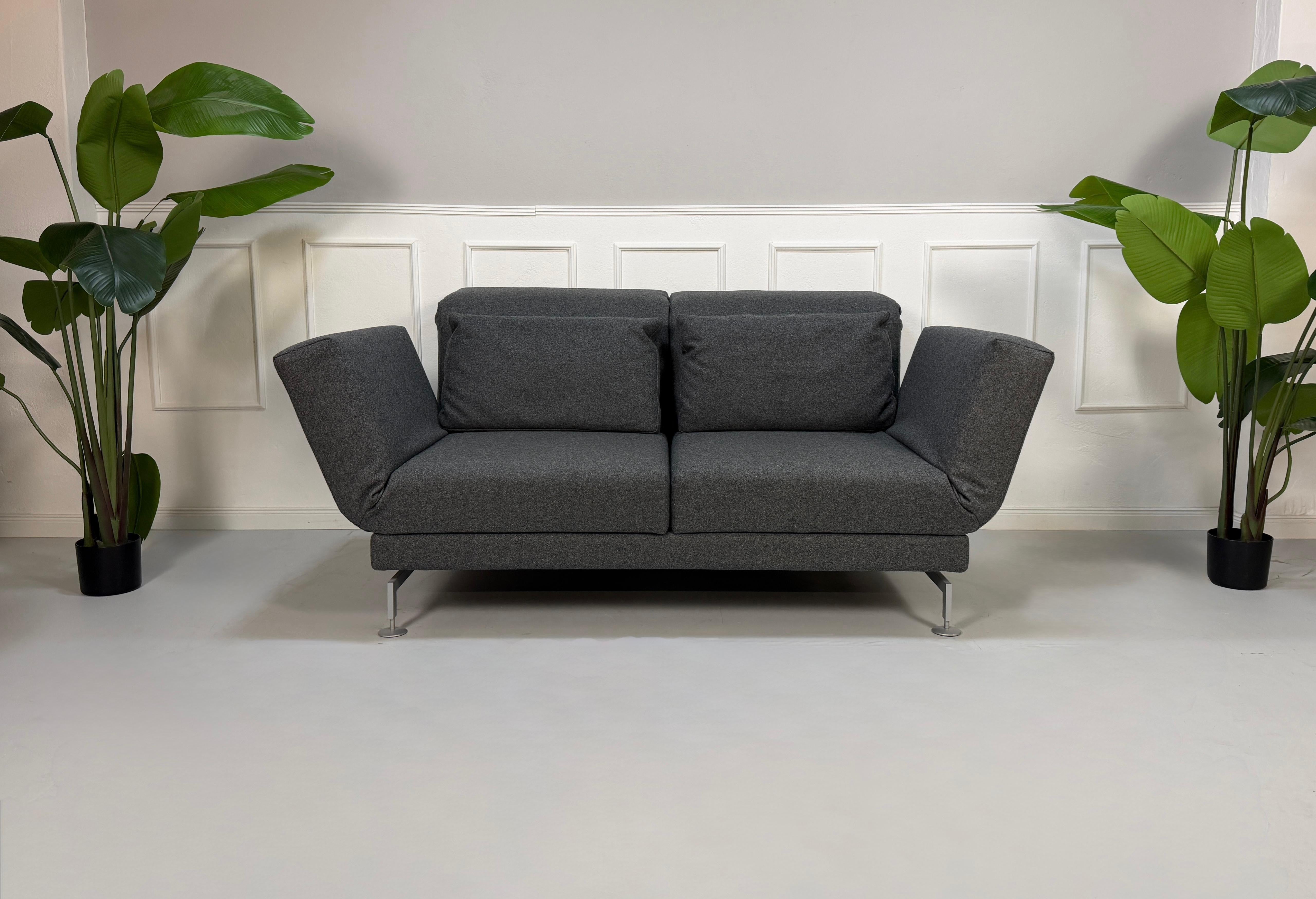 Graues Brühl Moule Ausstellungsstück Designer Stoff Sofa vor einer Wand, stilvoll und modern eingerichtet.