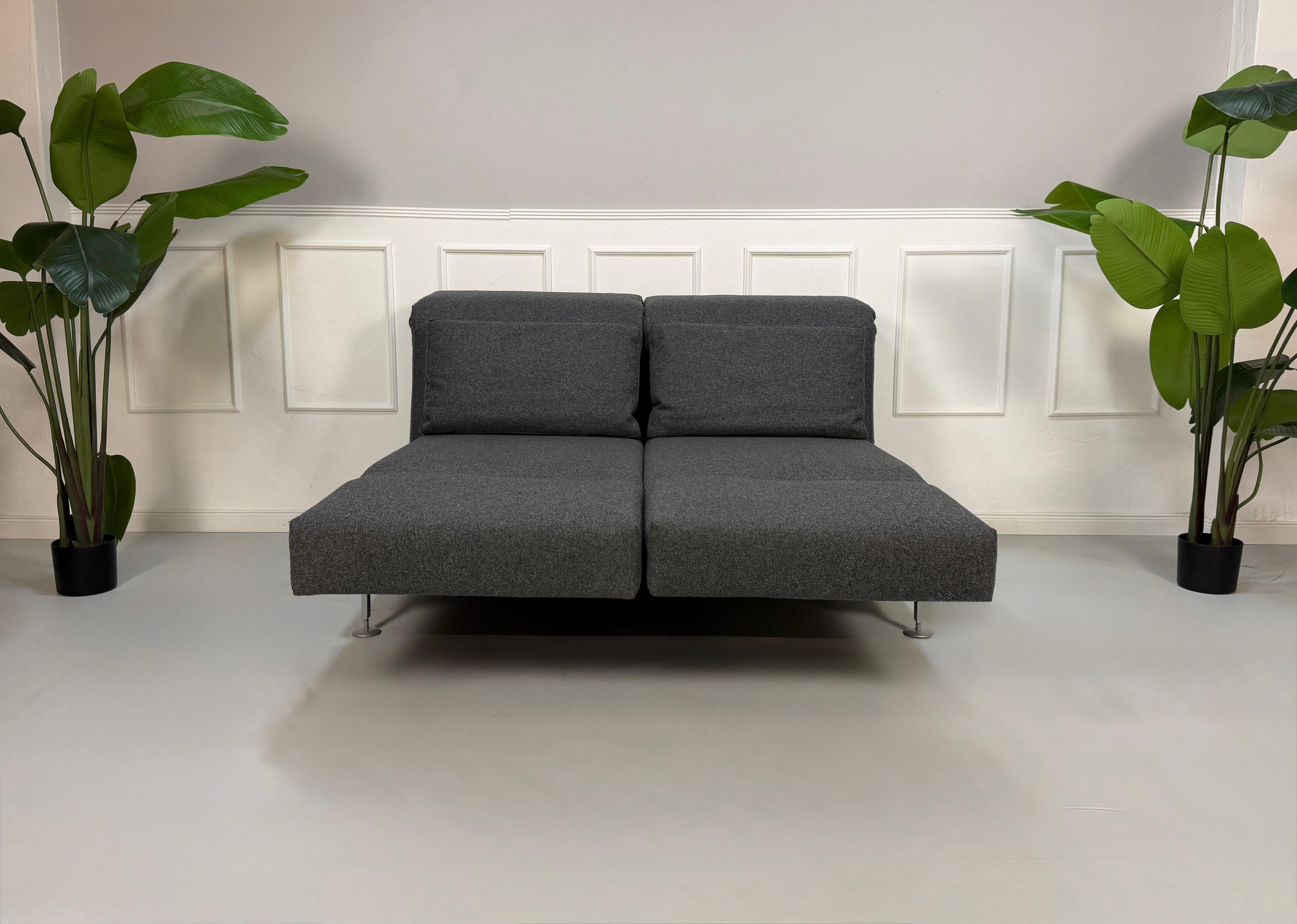 Graues Brühl Moule Ausstellungsstück Designer Stoff Sofa vor einer Wand, stilvoll und modern eingerichtet.