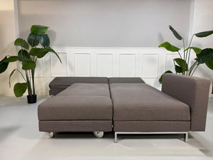 Gebrauchtes graues Brühl Four Two Designer Stoff Sofa vor einer Wand, stilvoll und modern eingerichtet.
