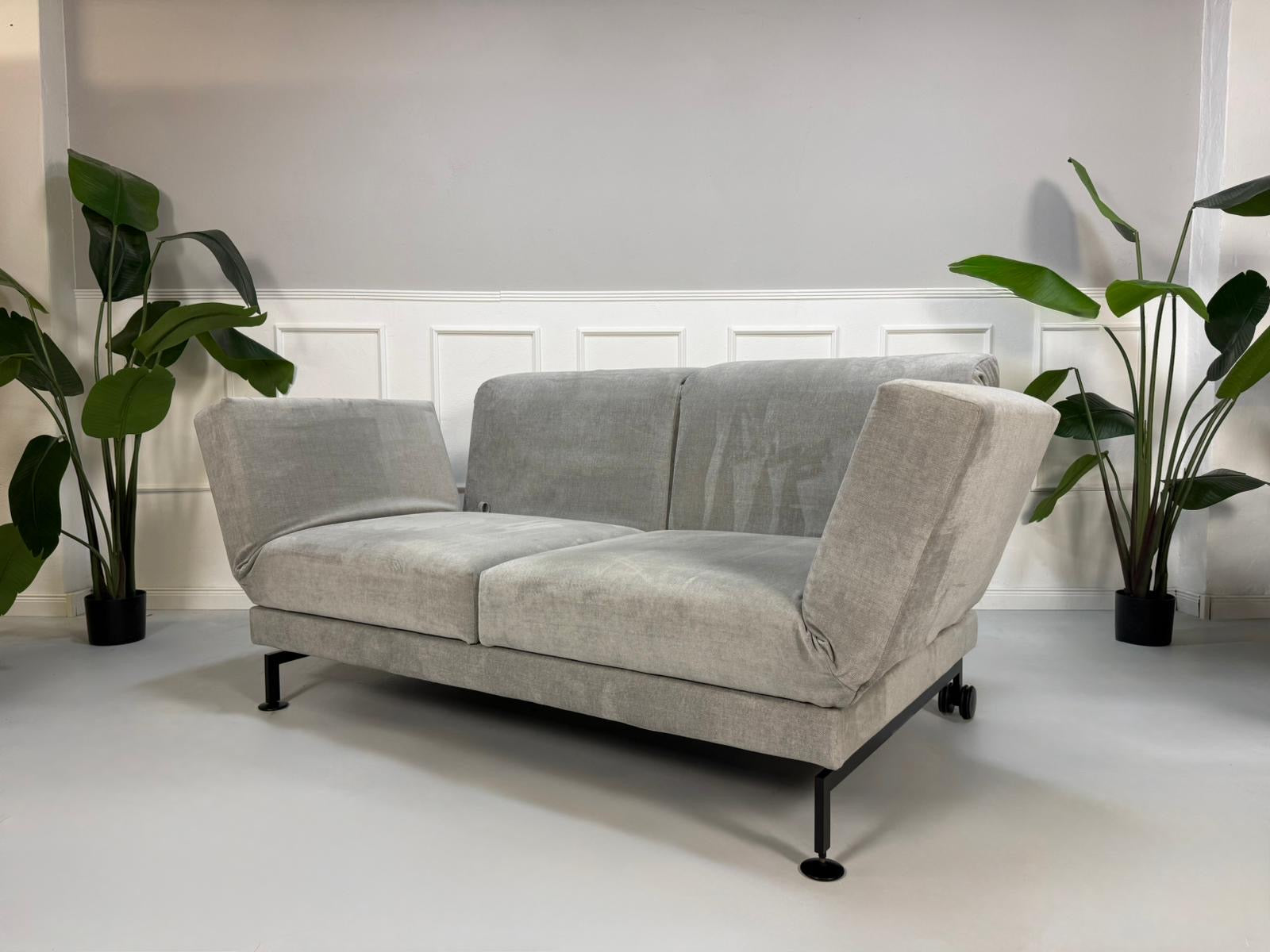 Gebrauchtes graues Brühl Moule Designer Stoff Sofa vor einer Wand, stilvoll und modern eingerichtet.