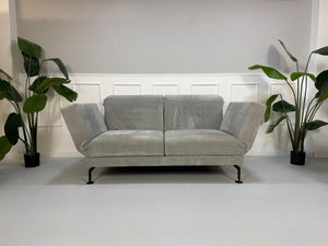 Gebrauchtes graues Brühl Moule Designer Stoff Sofa vor einer Wand, stilvoll und modern eingerichtet.