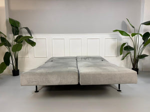 Gebrauchtes graues Brühl Moule Designer Stoff Sofa vor einer Wand, stilvoll und modern eingerichtet.
