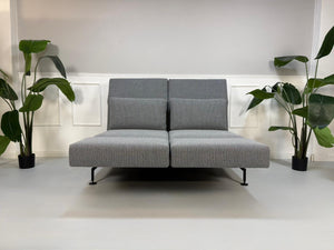 Gebrauchtes Brühl Moule Designer Stoff Sofa als Ausstellungsstück in der Farbe Grau vor einer Wand, stilvoll und modern eingerichtet.