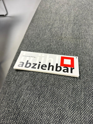 Gebrauchtes graues Brühl Moule Designer Stoff Sofa mit Hocker vor einer Wand, stilvoll und modern eingerichtet.