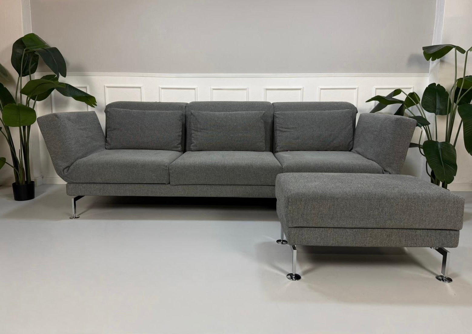 Gebrauchtes graues Brühl Moule Designer Stoff Sofa mit Hocker vor einer Wand, stilvoll und modern eingerichtet.